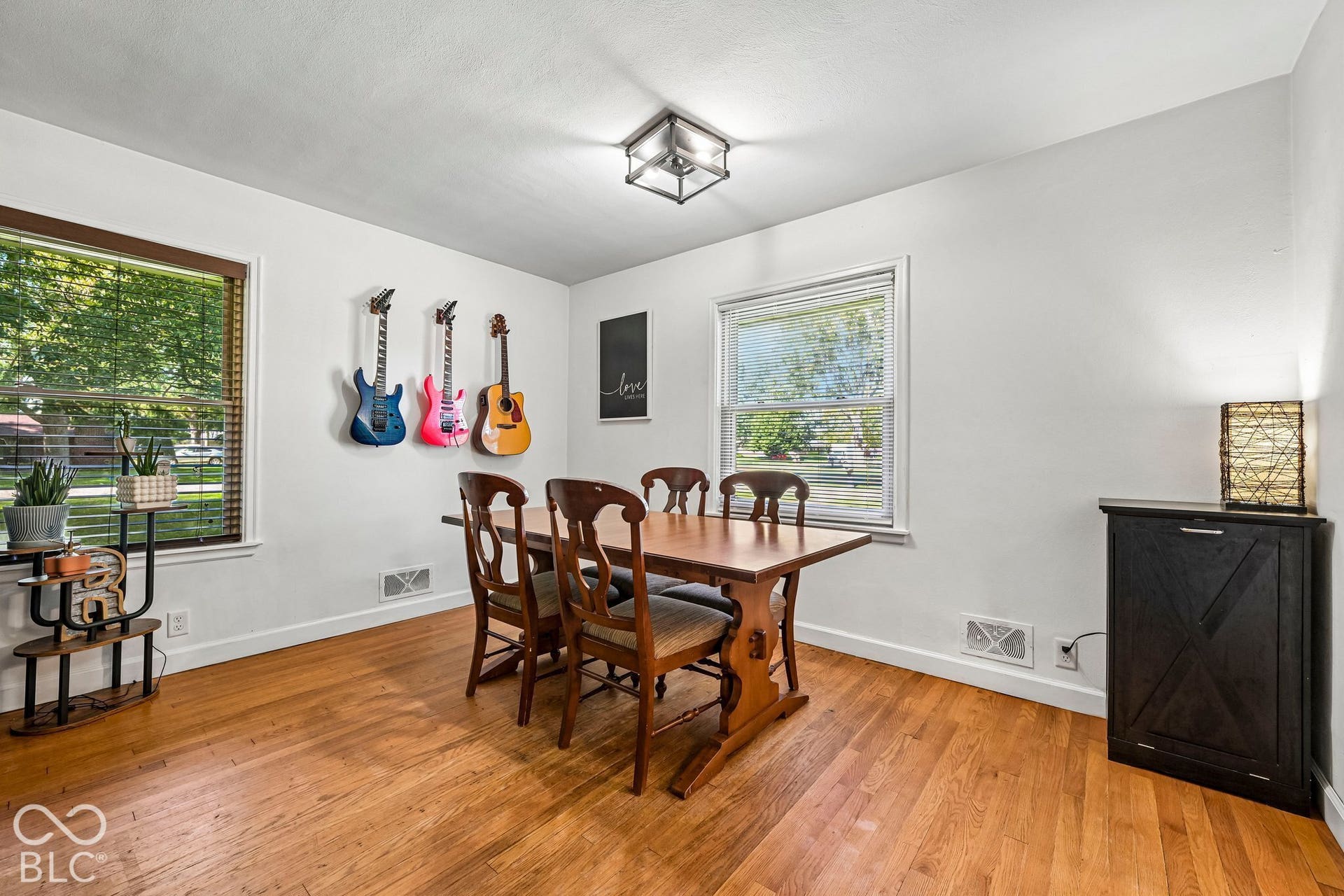 Hardwood-finish flooring throughout, white painted walls, and two large windows with blinds