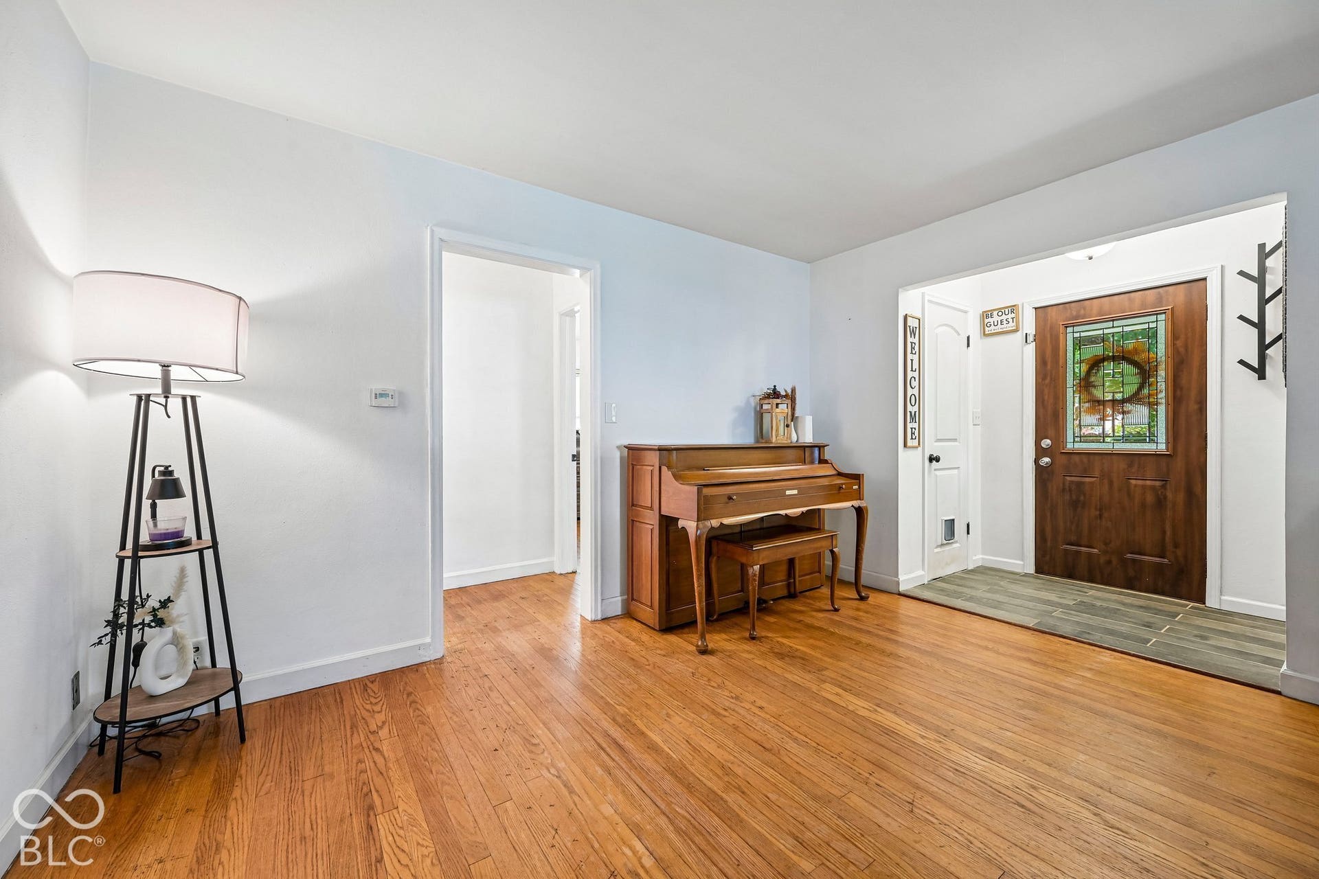 Hardwood flooring throughout, white painted walls, and a wood entry door with decorative glass