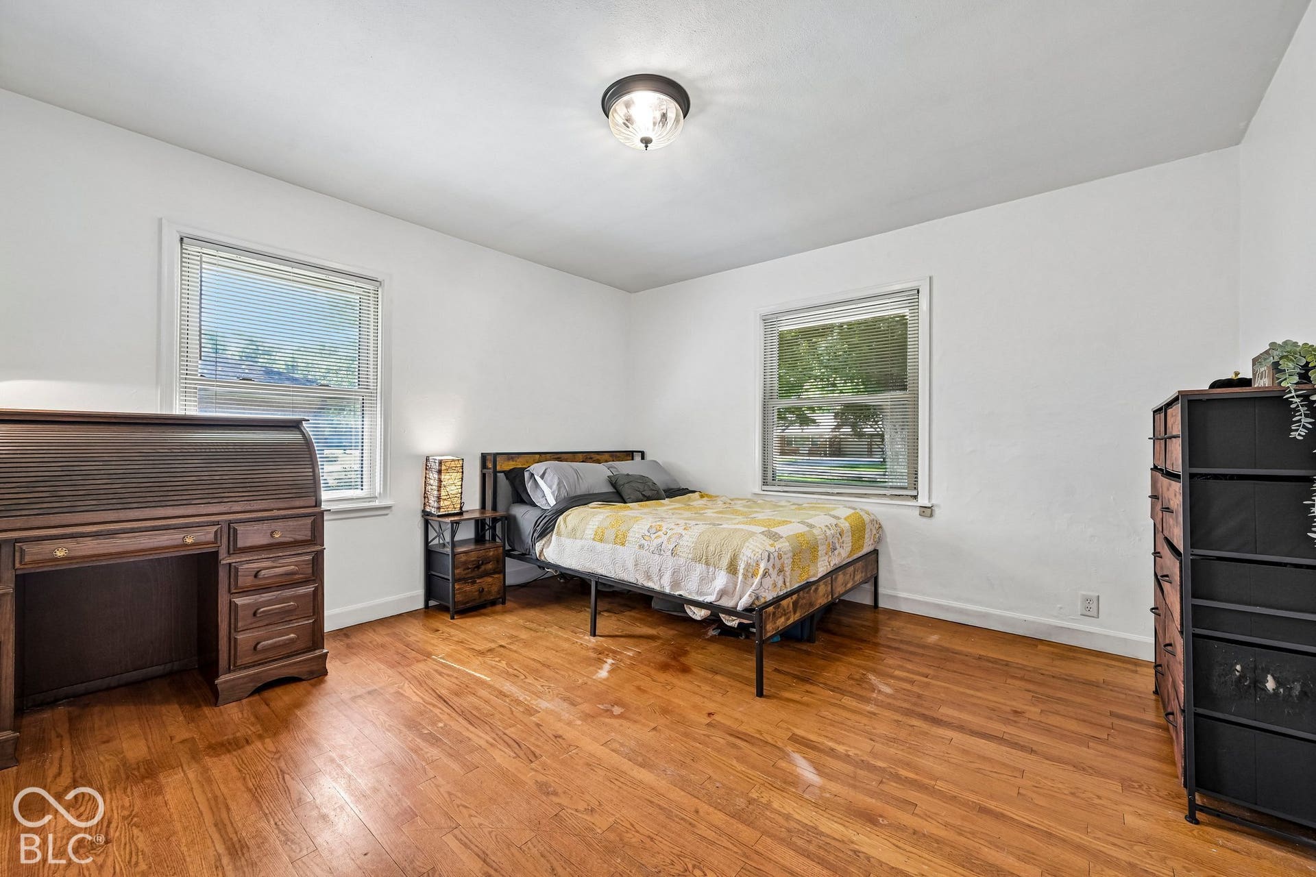 Hardwood flooring, painted white walls, two windows, and a flush mount ceiling light fixture
