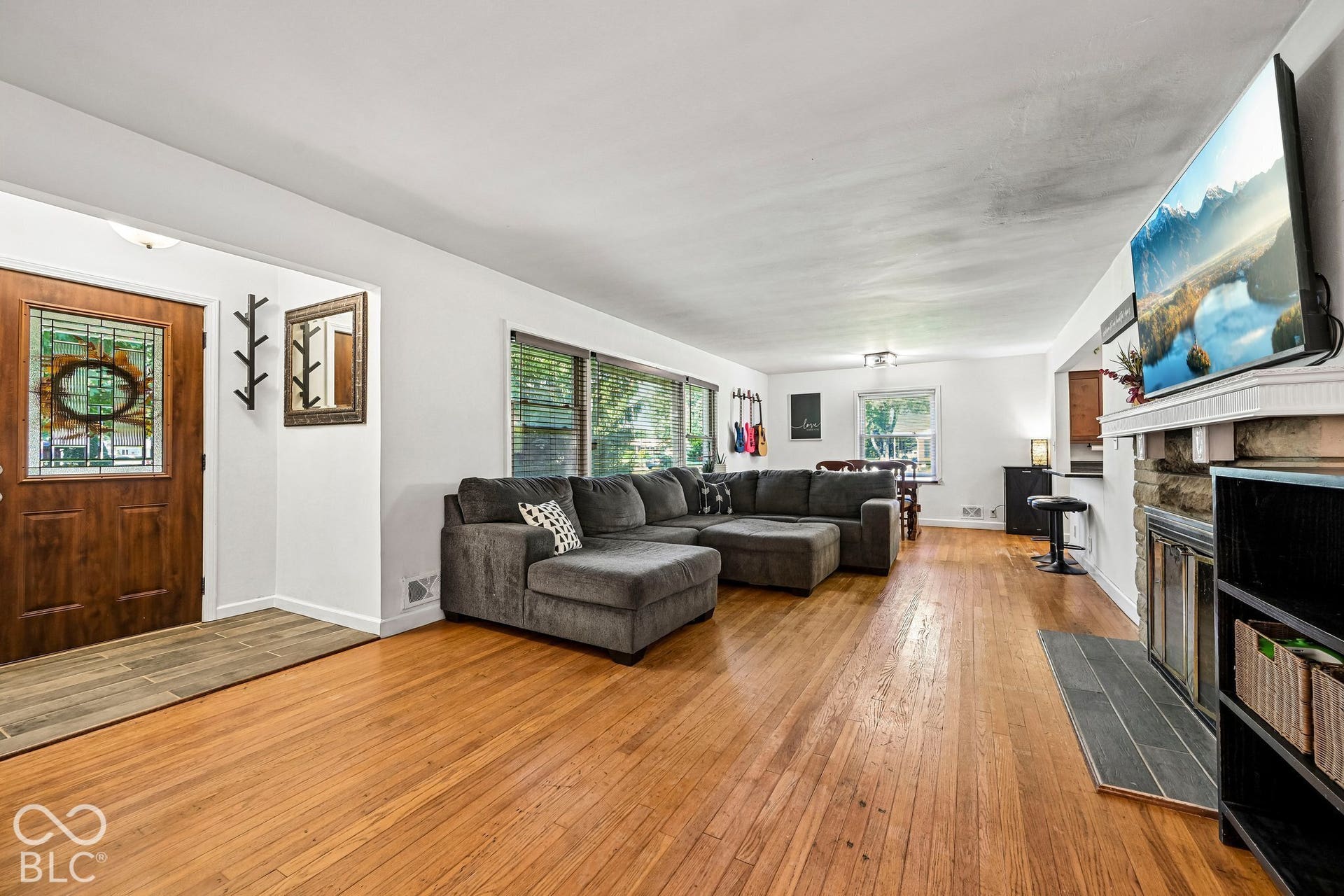 Wood-finish flooring throughout, stone-faced fireplace with hearth, and multiple windows