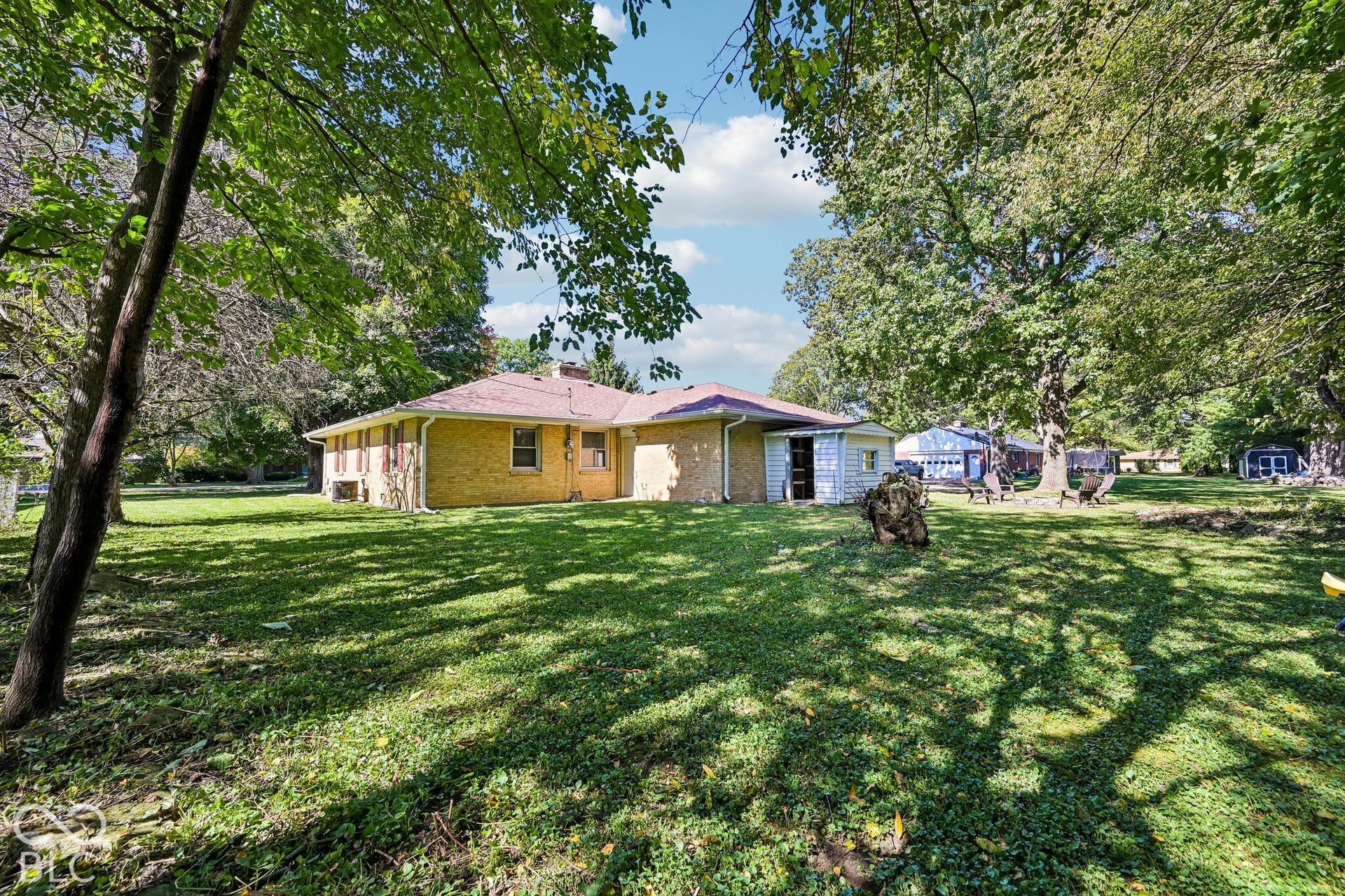 Expansive rear yard featuring mature trees, a detached shed, and a brick exterior residence