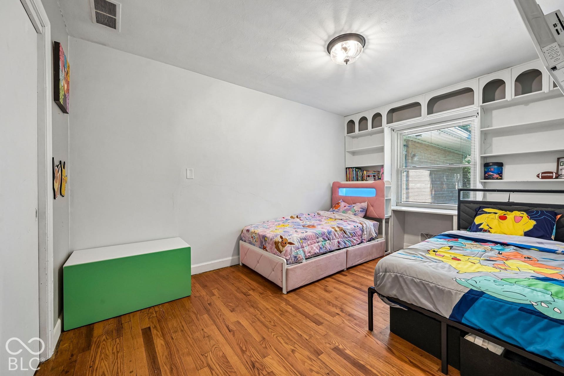 Hardwood flooring, built-in shelving, overhead light fixture, and a window with natural illumination