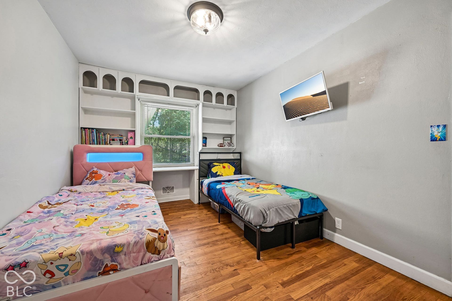 Built-in shelving surrounding a window, wood-finish flooring, and a ceiling-mounted light fixture