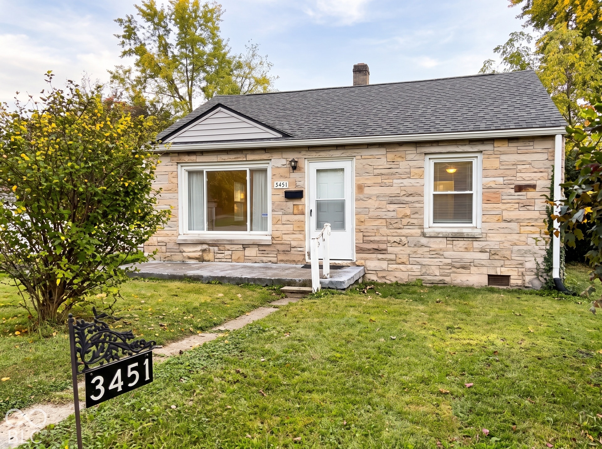 Stone veneer exterior with a gabled roof and white trim