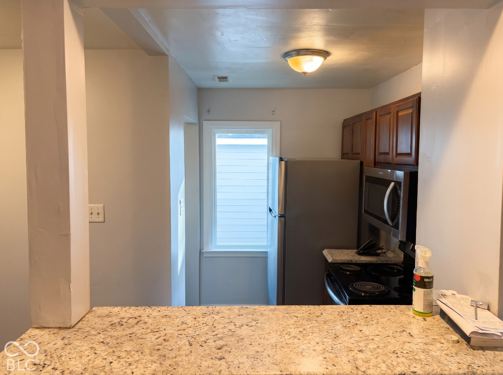 Kitchen featuring rich wood-finish cabinetry, stainless steel appliances, and a polished stone-finish countertop