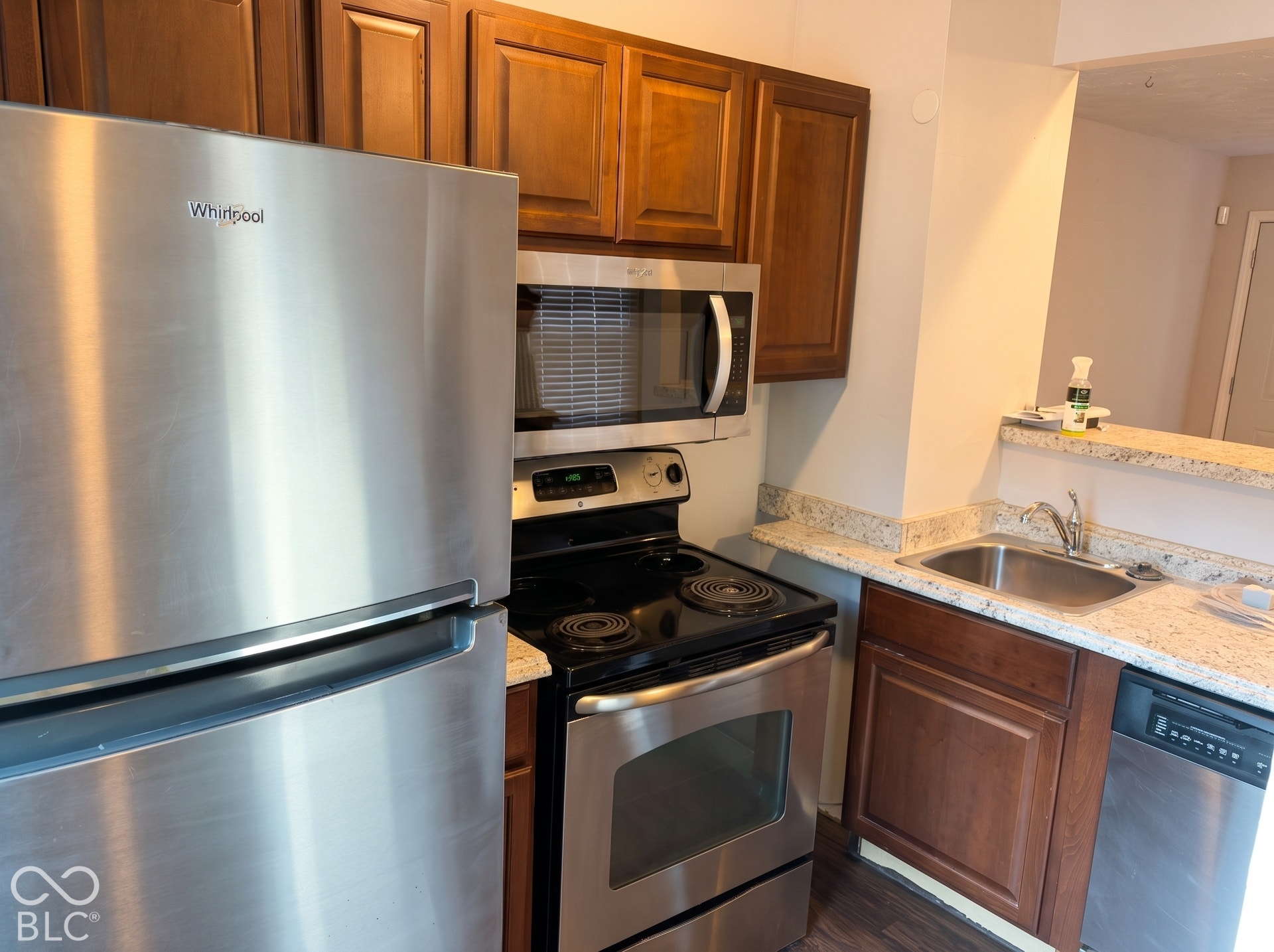 Kitchen featuring wood-finish cabinetry, stainless steel appliances, speckled countertops, and a stainless steel sink