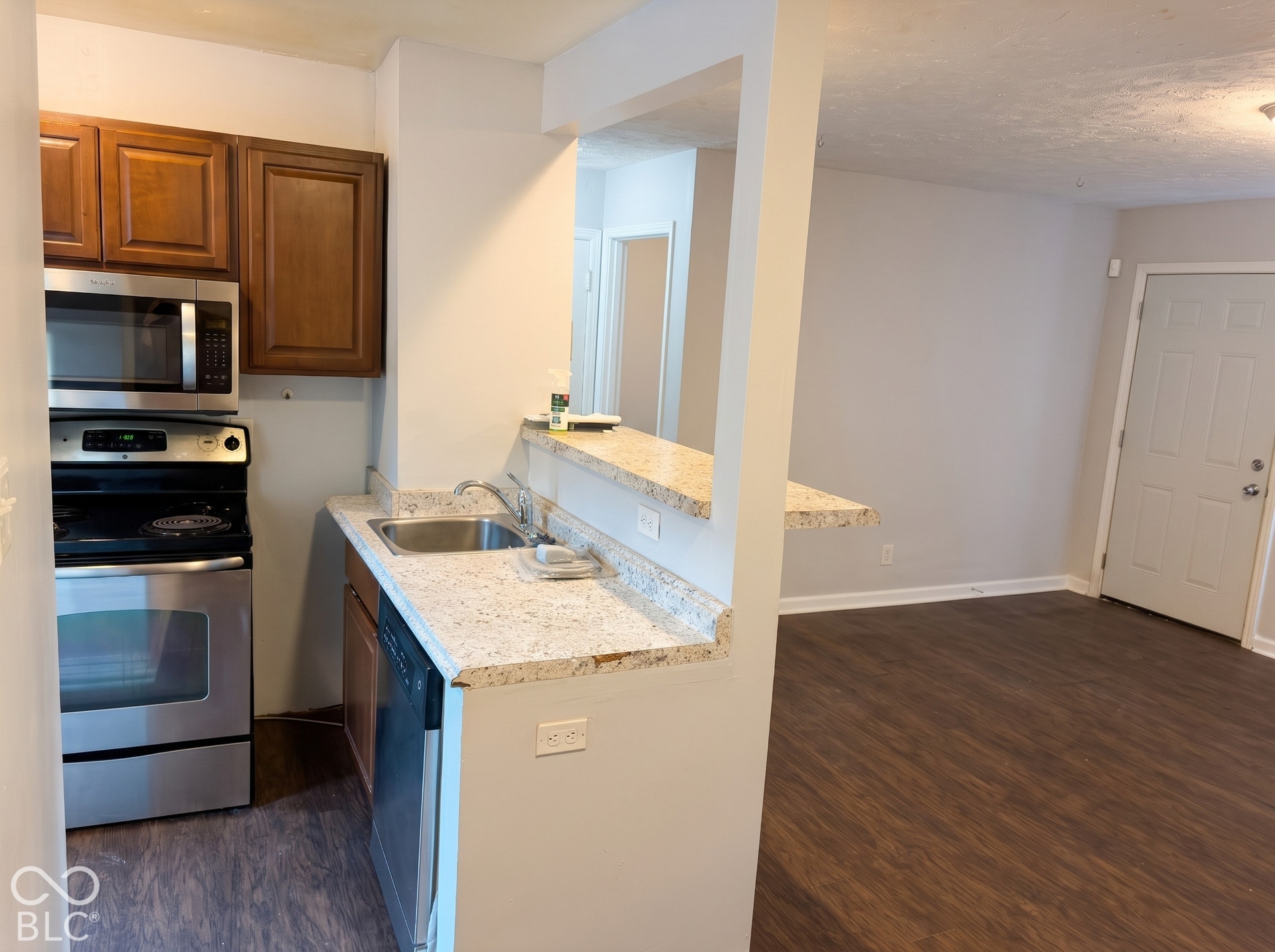 Kitchen featuring stainless steel appliances, wood-finish cabinetry, a stainless steel sink, and light-toned countertops