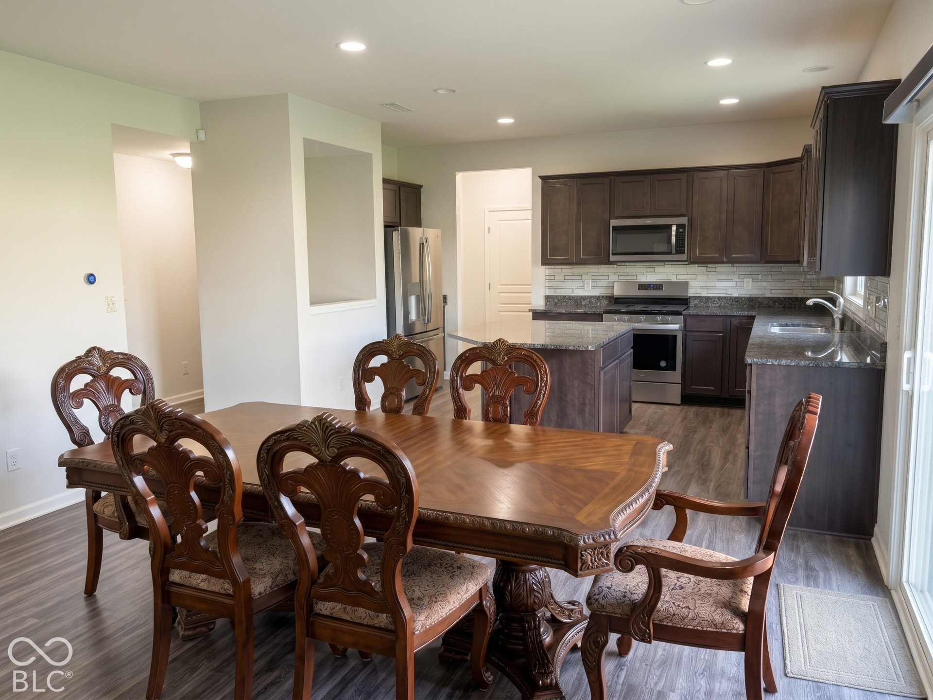 Virtually Altered - Kitchen featuring dark wood cabinetry, granite countertops, and stainless steel appliances