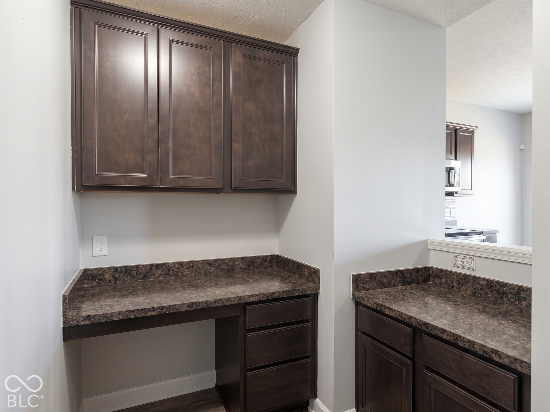 Virtually Altered - Built-in desk area featuring dark wood-finish cabinetry and a complementary countertop