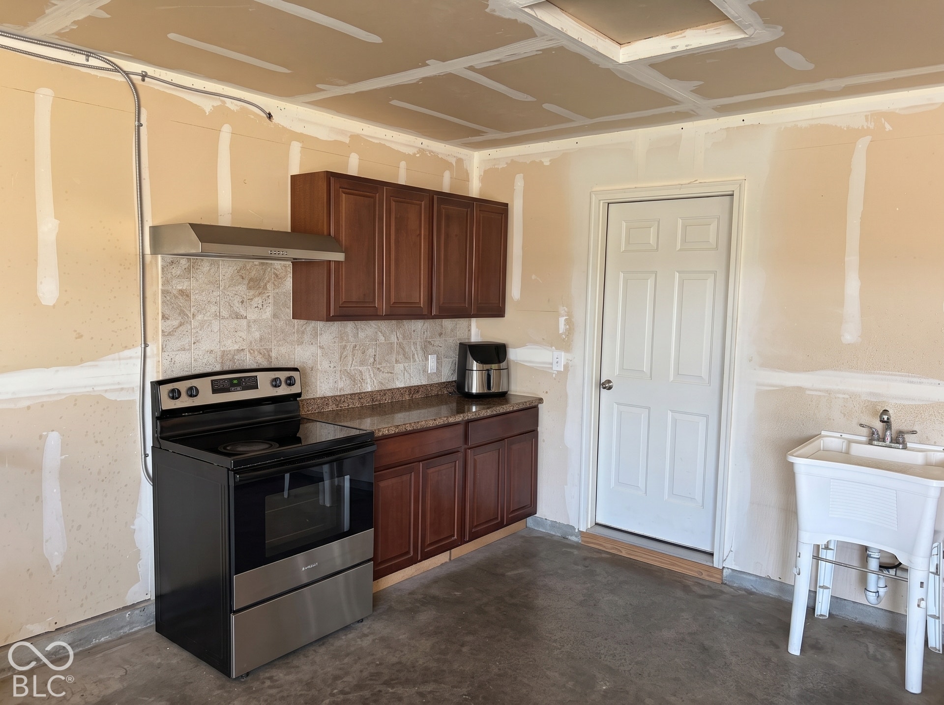 Virtually Altered - Garage kitchen with built-in range hood and cabinets