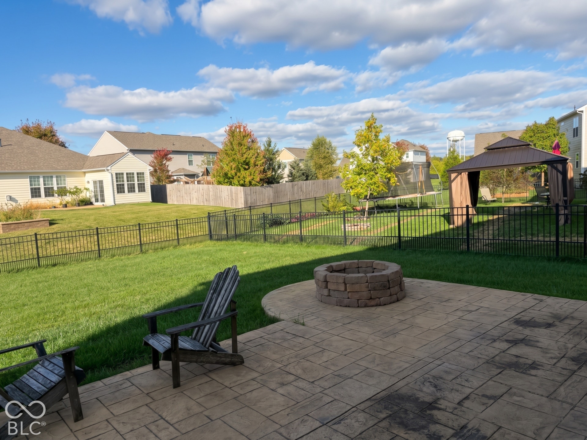 Virtually Altered - Stamped concrete patio with a built-in fire pit, extensive fenced yard