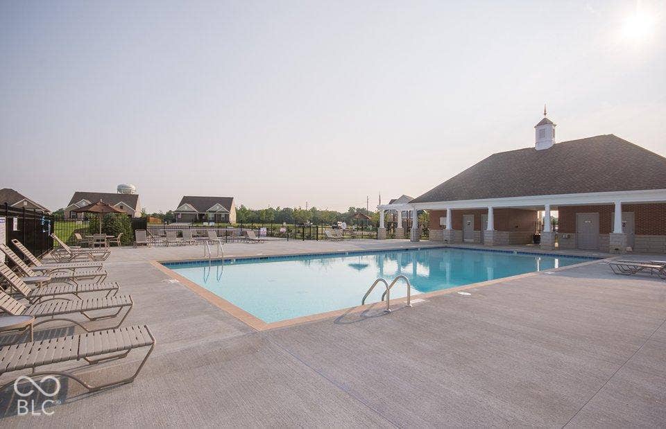Community swimming pool with concrete surround, integrated pool steps, and an adjacent brick-clad pavilion featuring a cupola