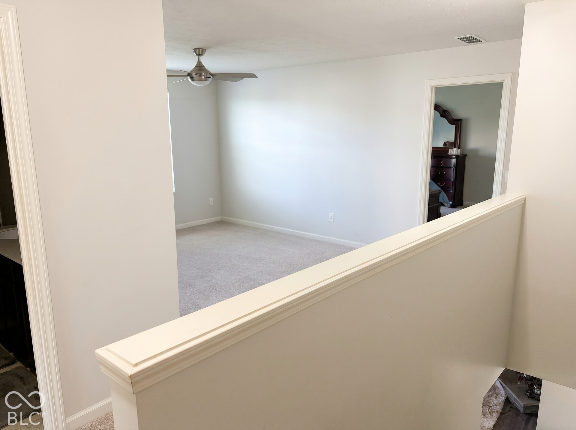 Virtually Altered - Carpeted interior space featuring a ceiling fan and white wall finishes