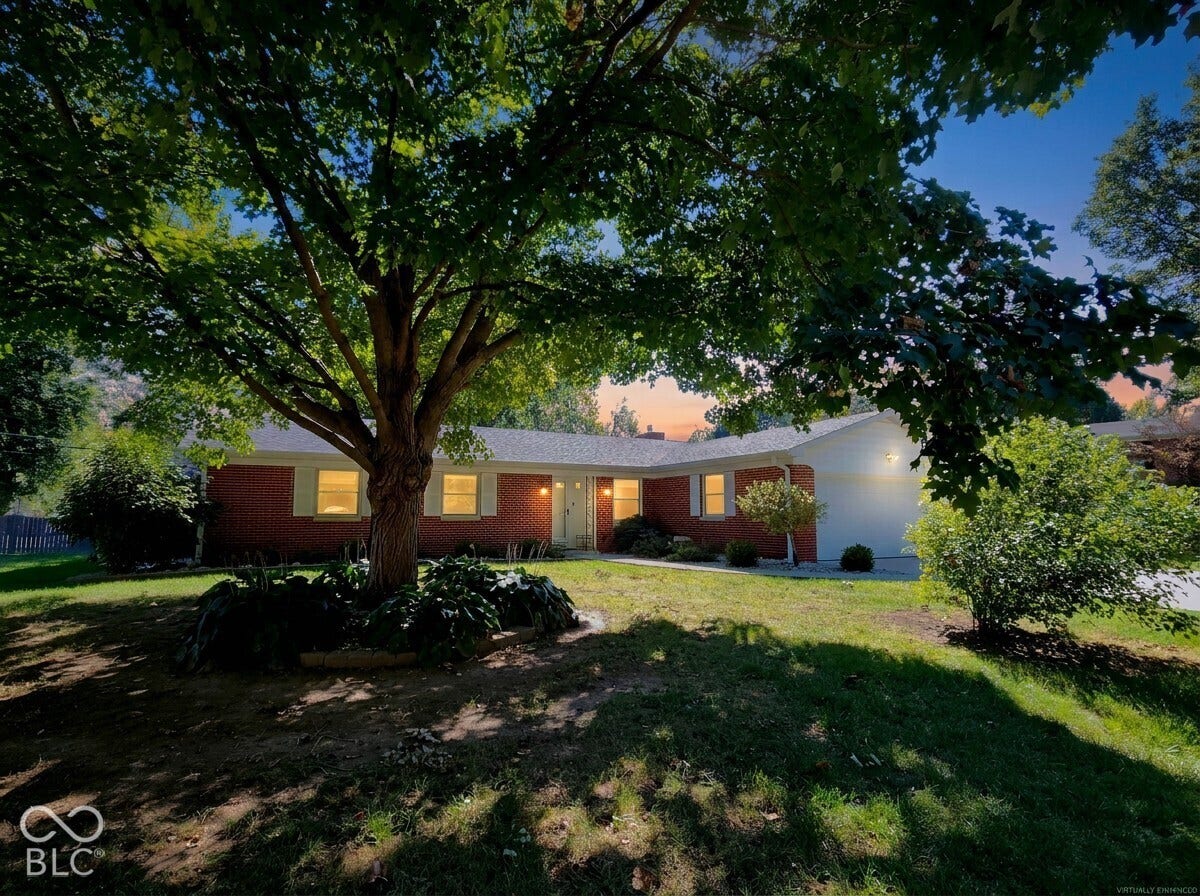 Virtually Altered - Brick facade residence with a white garage door, mature landscaping, and a manicured lawn