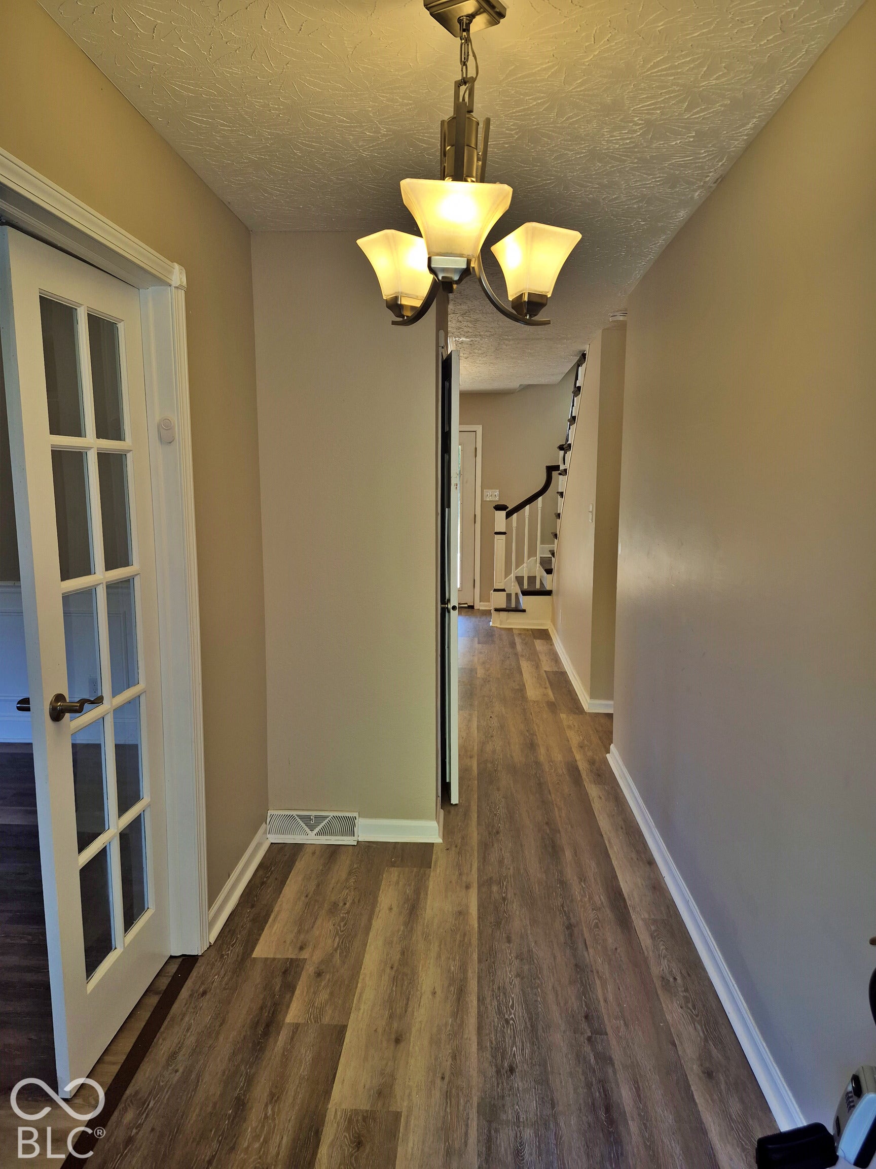 Hallway featuring wood-finish flooring, a contemporary chandelier, and a French door entry