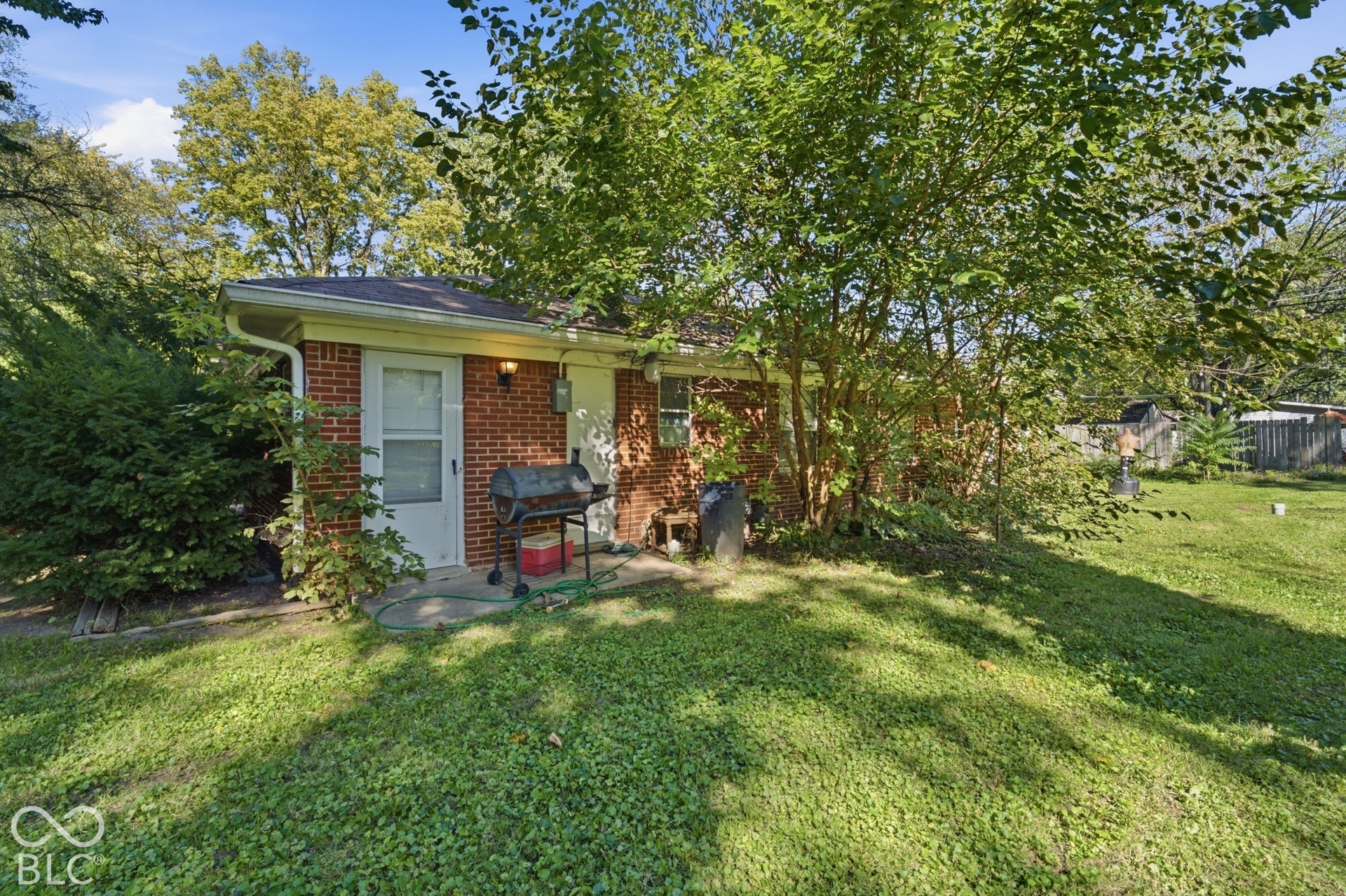 1273 Farley, Indianapolis, IN 46214 Brick exterior with a white storm door, concrete patio, and a manicured lawn