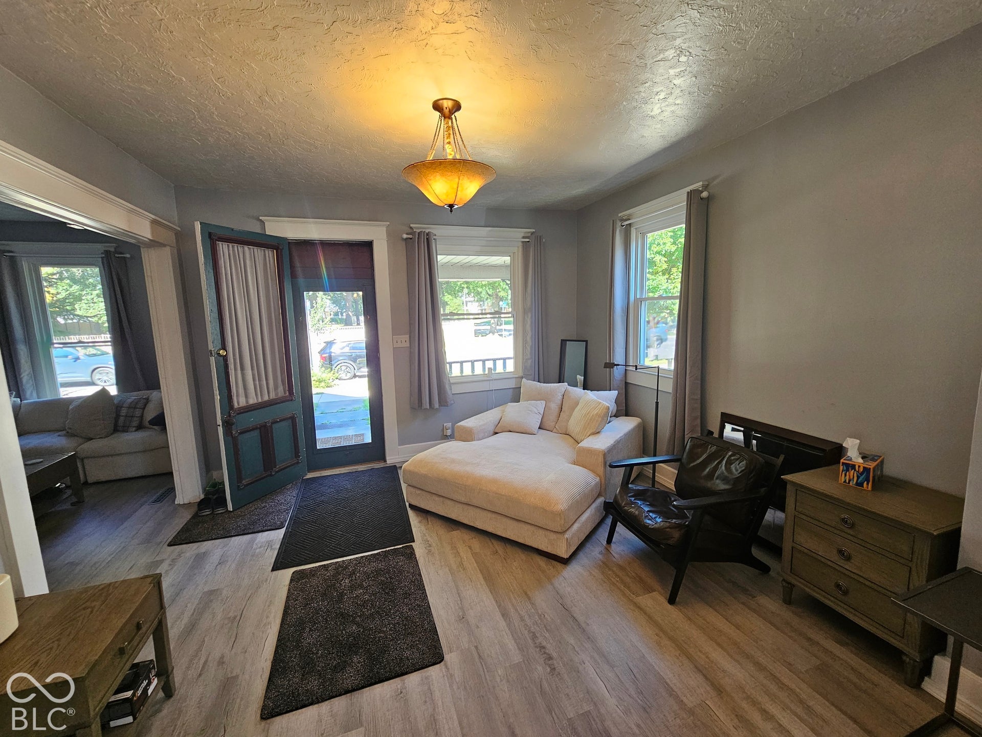 917 W 8th Street, Anderson, IN 46016 Wood-finish flooring throughout, light gray wall color, multiple windows, and a decorative ceiling light fixture