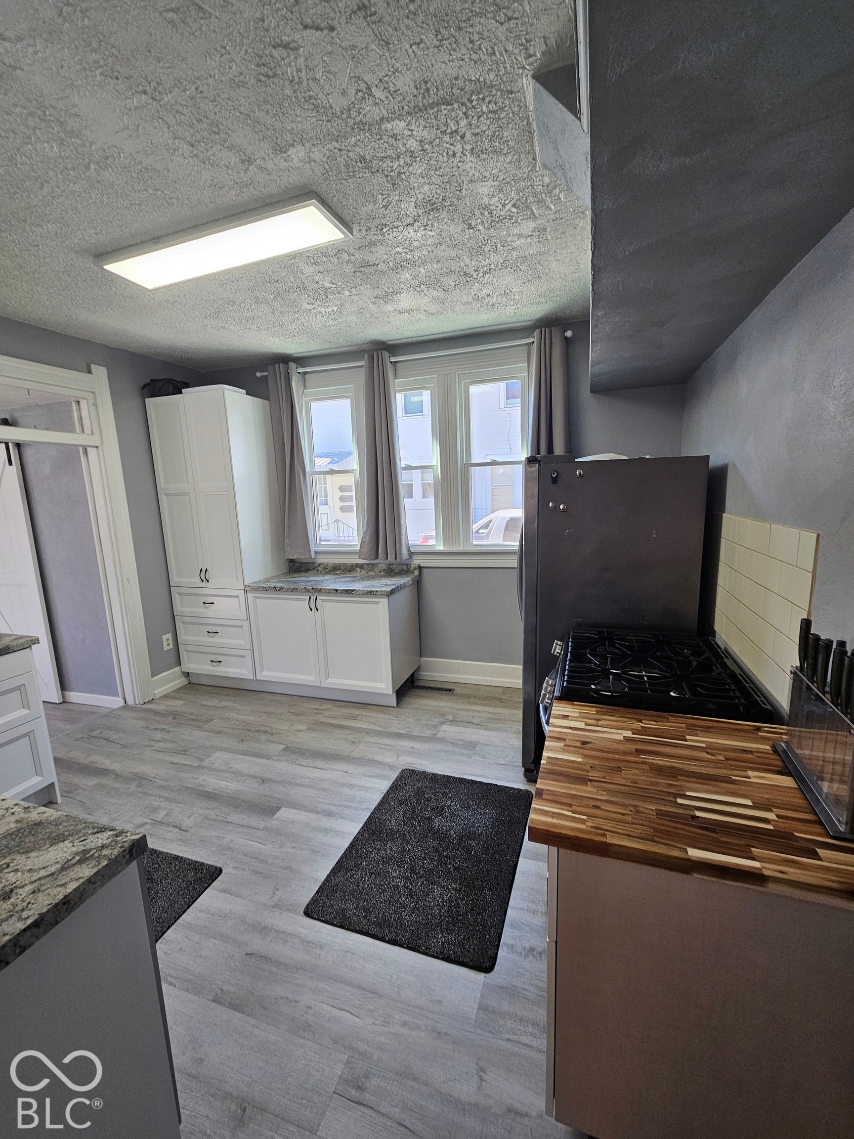 917 W 8th Street, Anderson, IN 46016 Modern kitchen featuring light wood-finish flooring, white cabinetry, dark stone-finish countertops, and a butcher block countertop