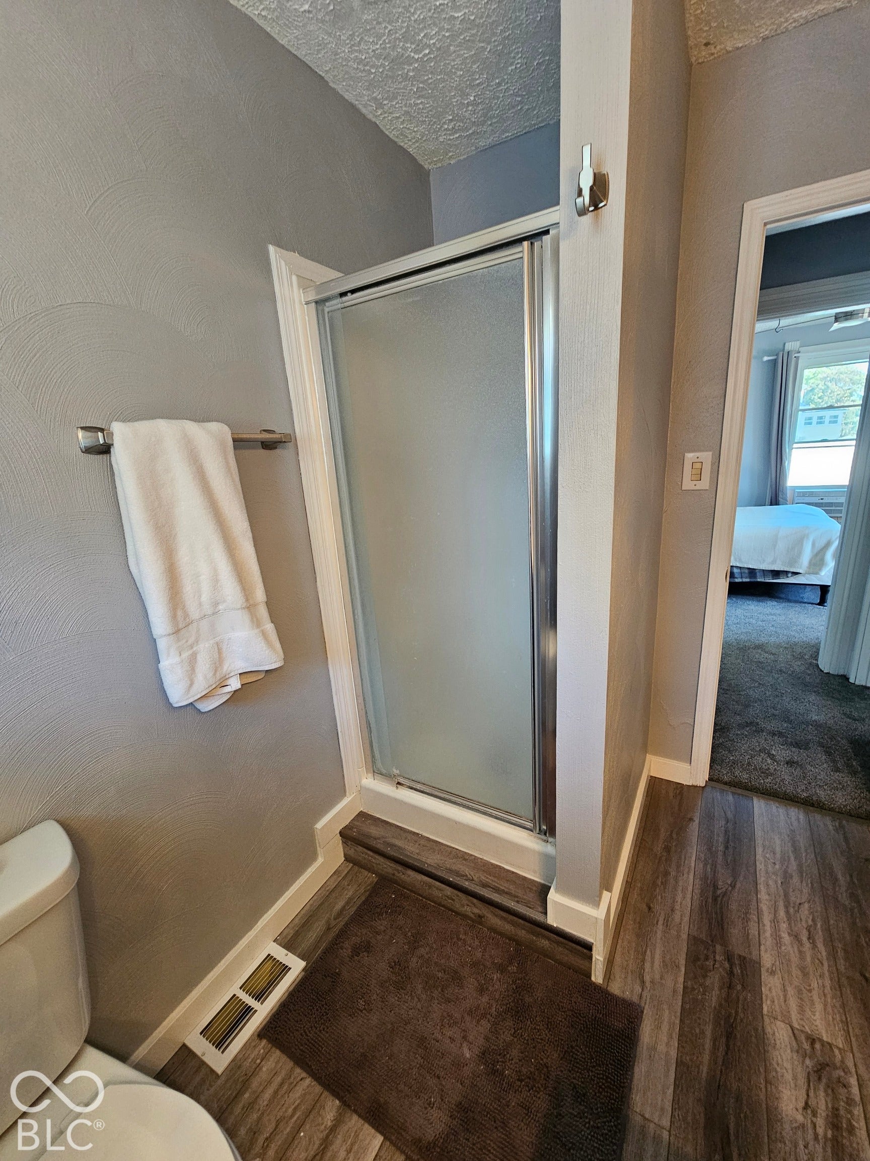 917 W 8th Street, Anderson, IN 46016 Shower enclosure with frosted glass door, brushed nickel towel bar, and wood-finish flooring