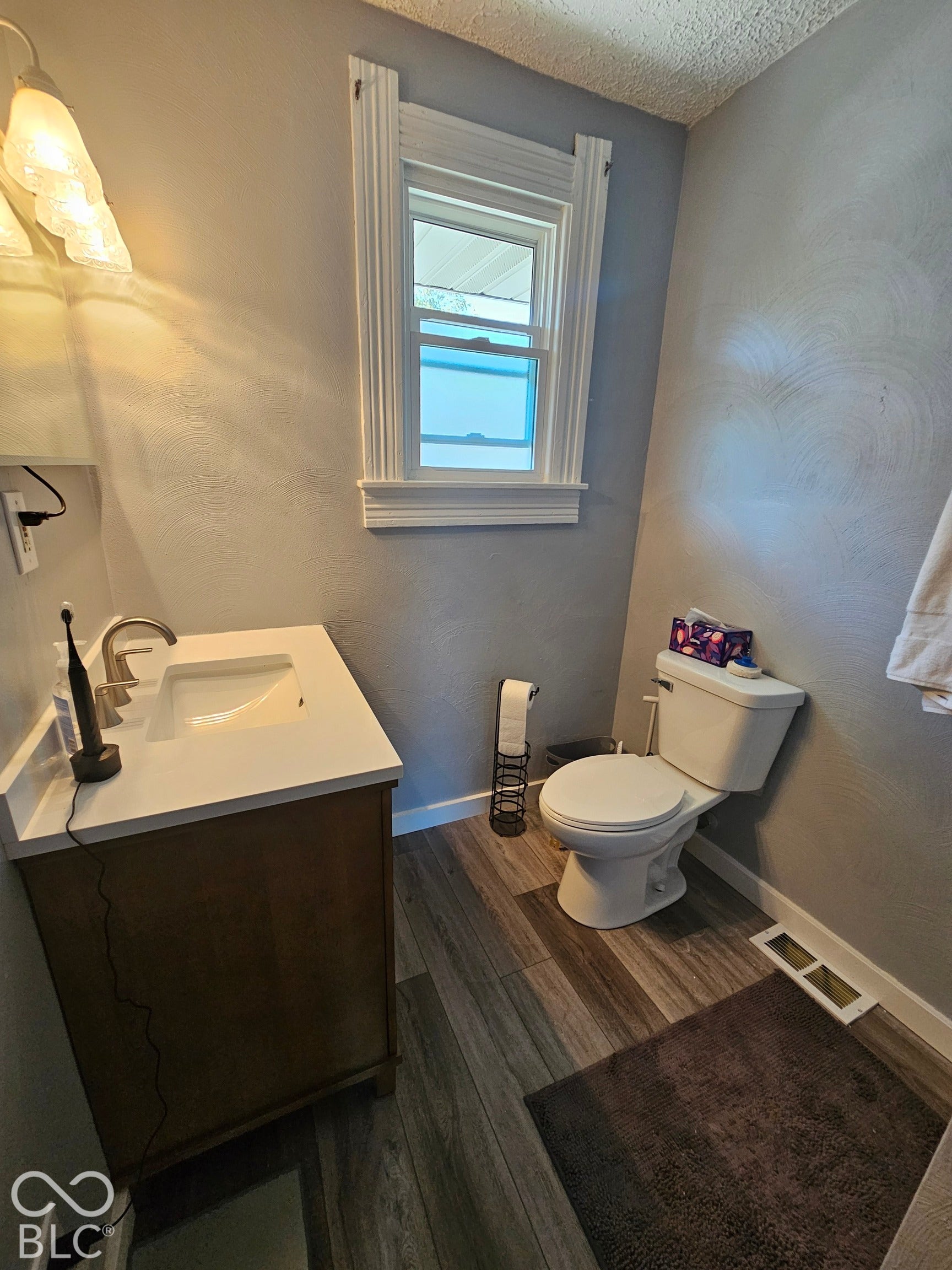 917 W 8th Street, Anderson, IN 46016 Vanity with an integrated sink and light-colored countertop, wood-finish flooring, and a window with white trim