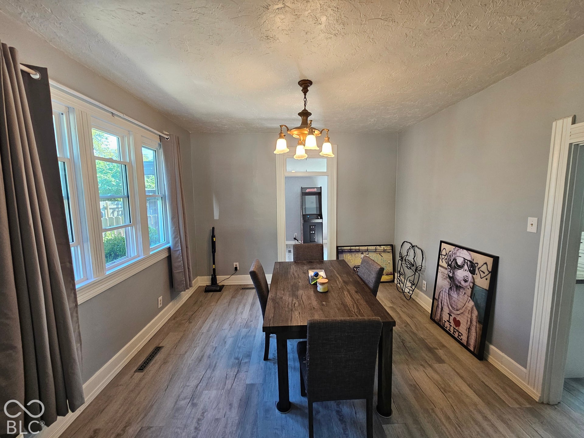 917 W 8th Street, Anderson, IN 46016 Spacious room featuring wood-finish flooring, a multi-pane window, and a chandelier-style ceiling fixture