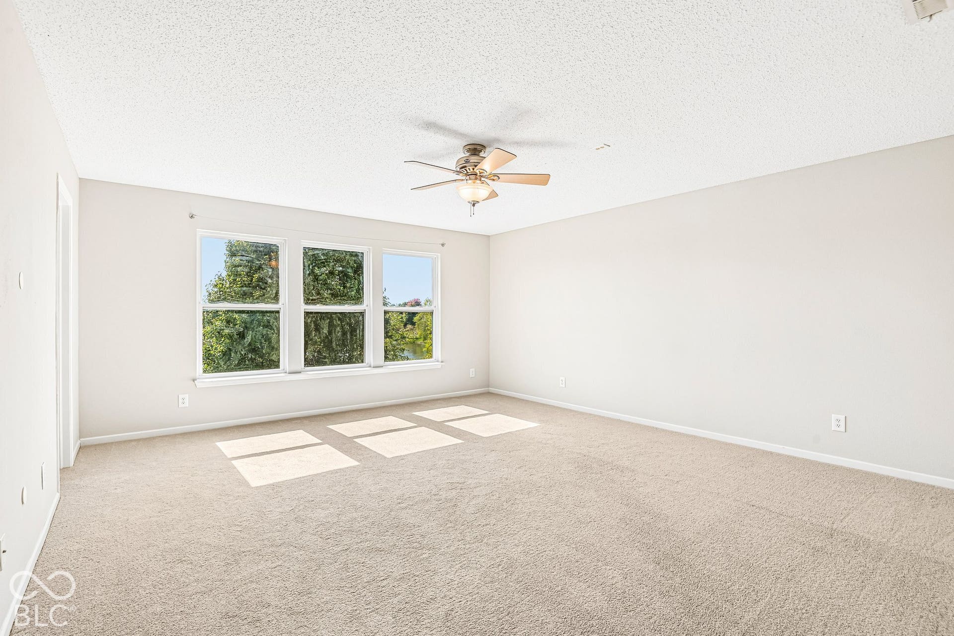 Neutral-toned carpeted flooring, white walls, and a ceiling fan with integrated lighting