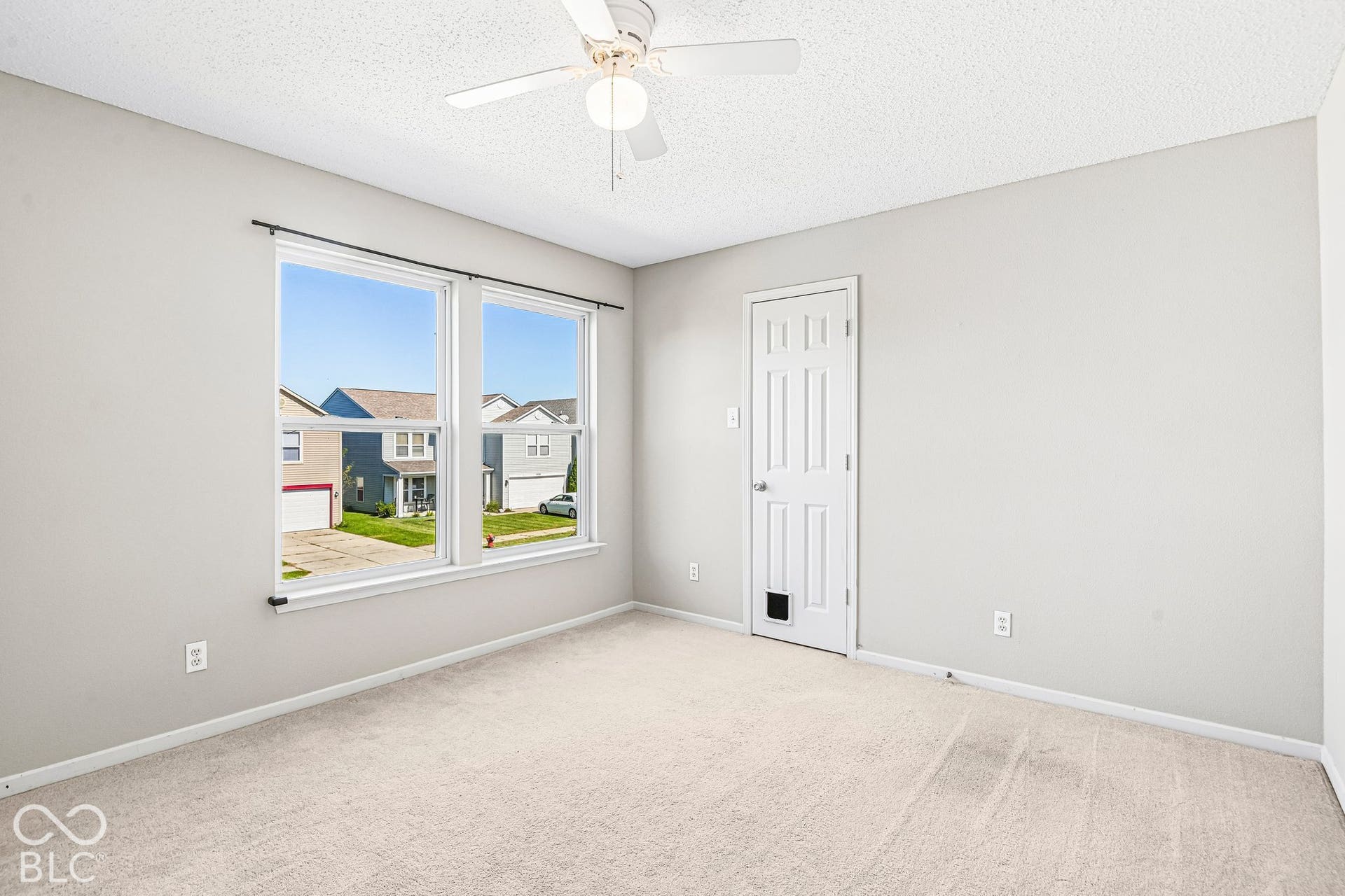 Neutral wall paint with carpet flooring, featuring a ceiling fan and a multi-pane window
