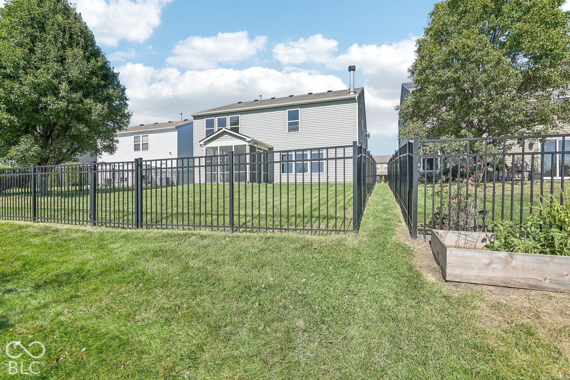 Fully fenced rear yard with a black metal fence, and a raised garden bed