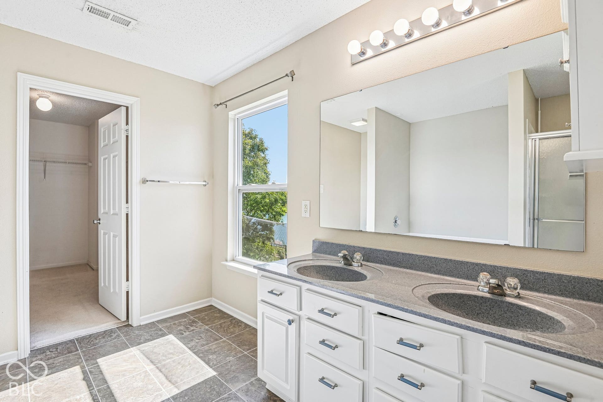 Dual vanity with integrated sinks, white cabinetry, and an expansive mirror