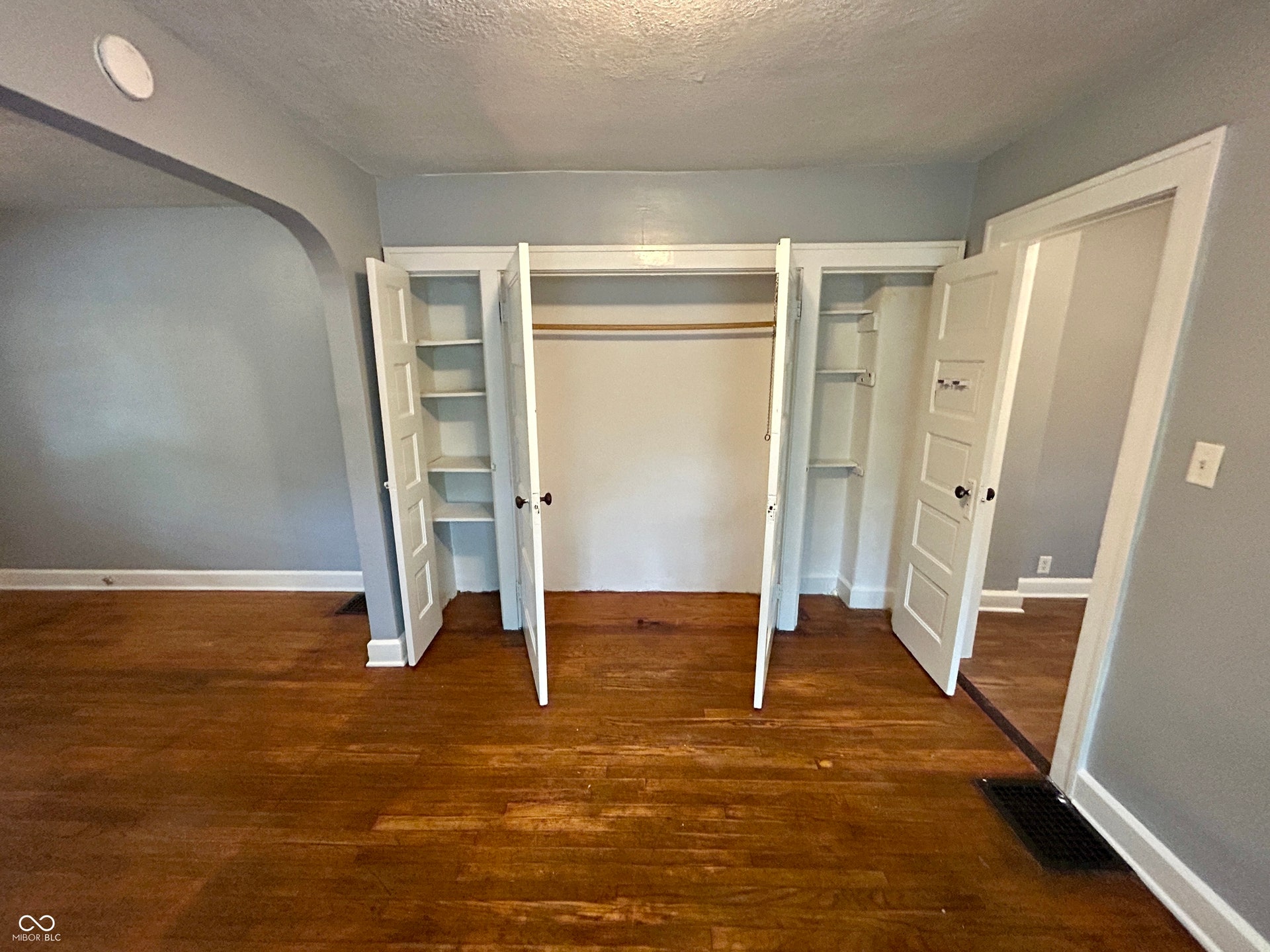 Integrated closet storage featuring bi-fold doors, shelving, and a hanging rod
