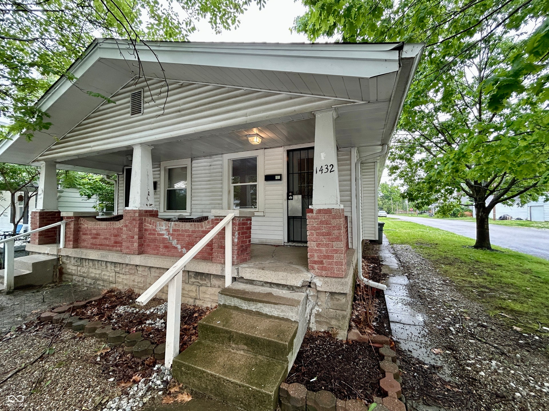 Front facade featuring white vinyl siding and a covered porch