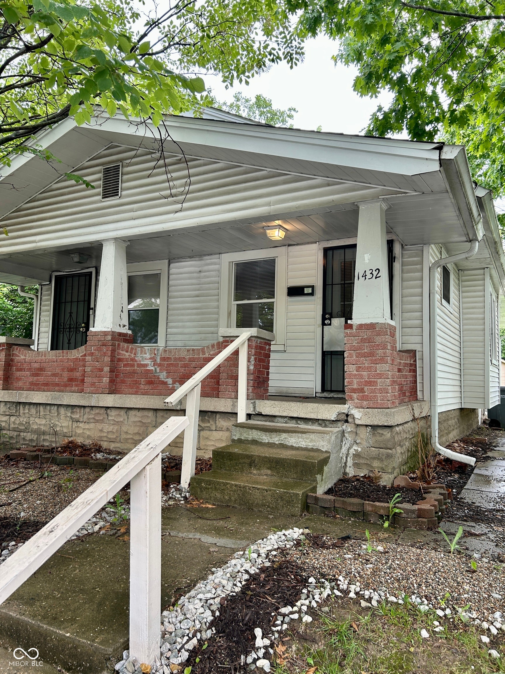 Single-story home featuring a front porch with brick pillars and concrete steps
