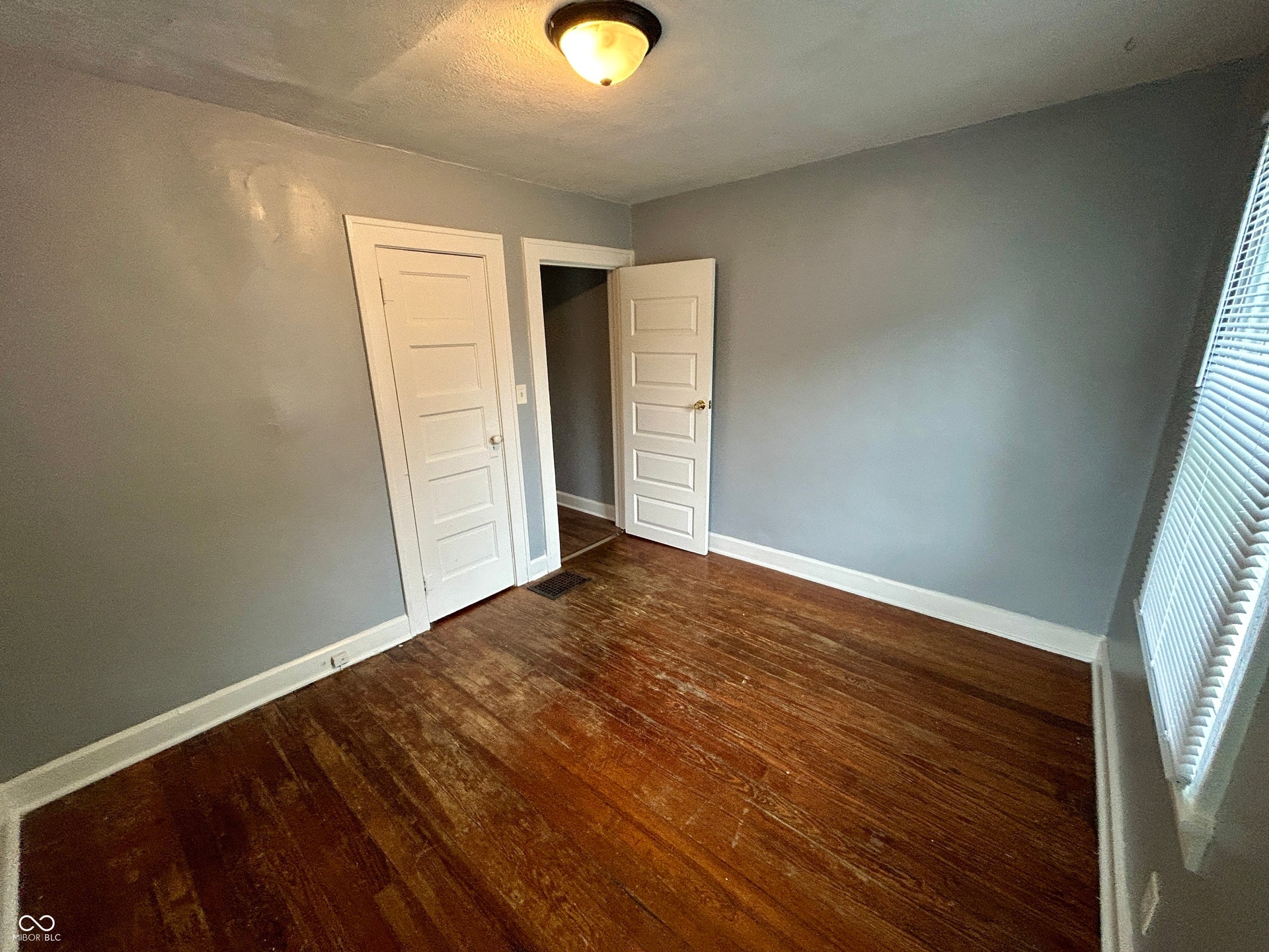 Room with wood-finish flooring, light grey walls, and white trim