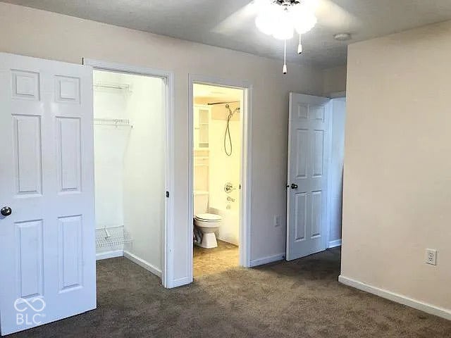Carpeted flooring with a ceiling fan, a walk-in closet with wire shelving, and a full bathroom with a tub and shower combination