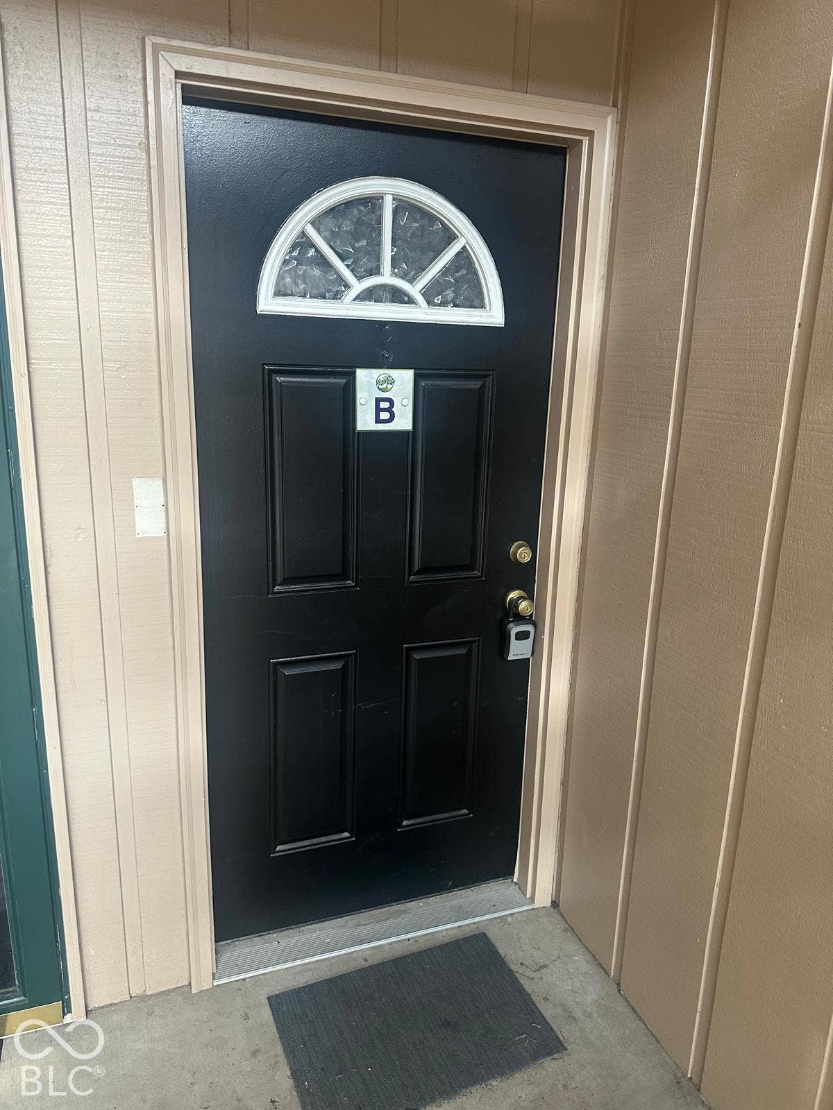 Black paneled entry door with an arched decorative window