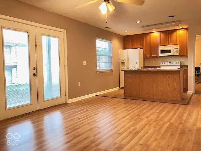Wood-finish flooring throughout, French doors with full-lite panels, kitchen with wood cabinetry, stainless steel sink, and a built-in microwave