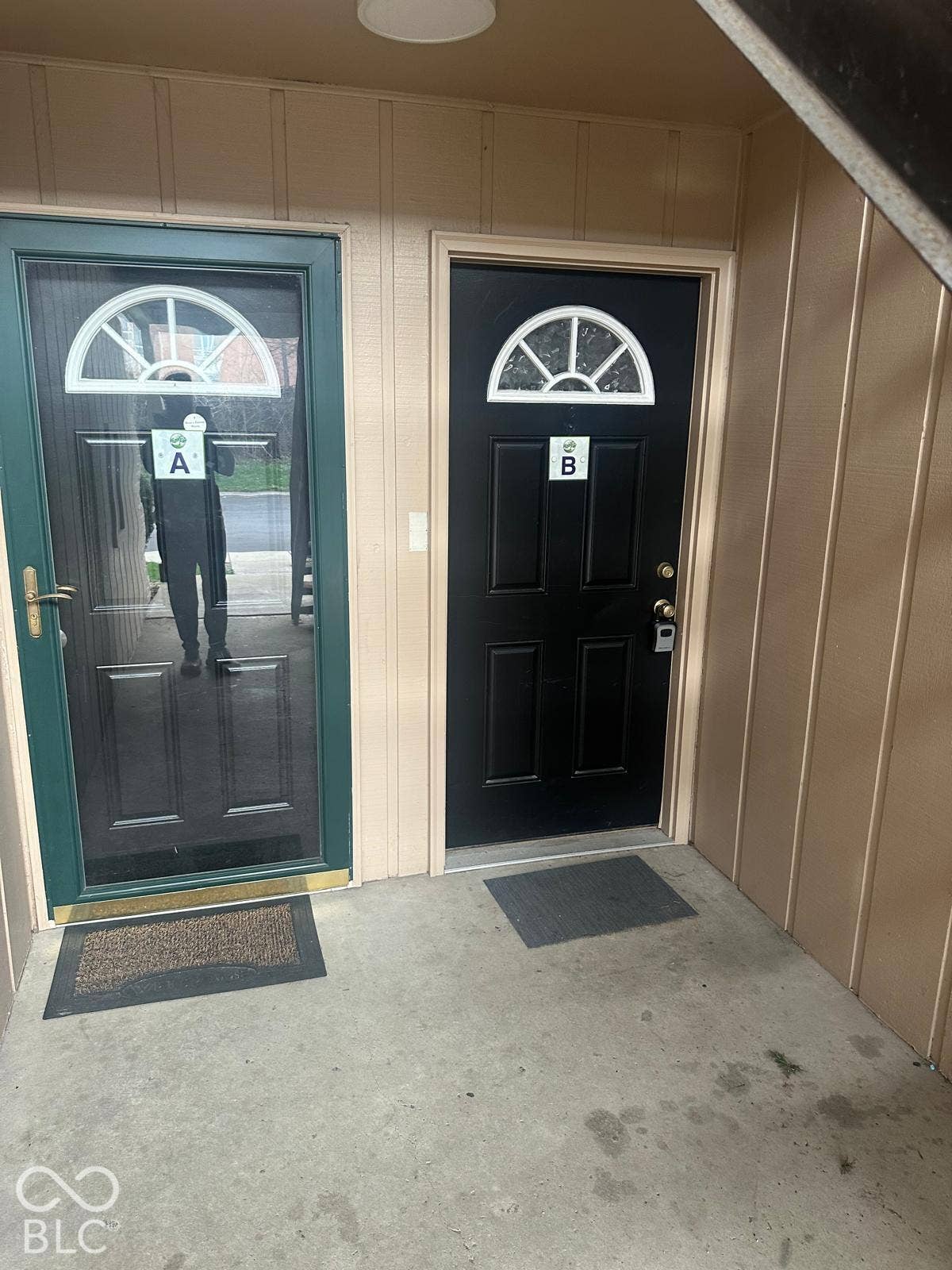 Two entry doors, one with a screen door, and vertical panel siding