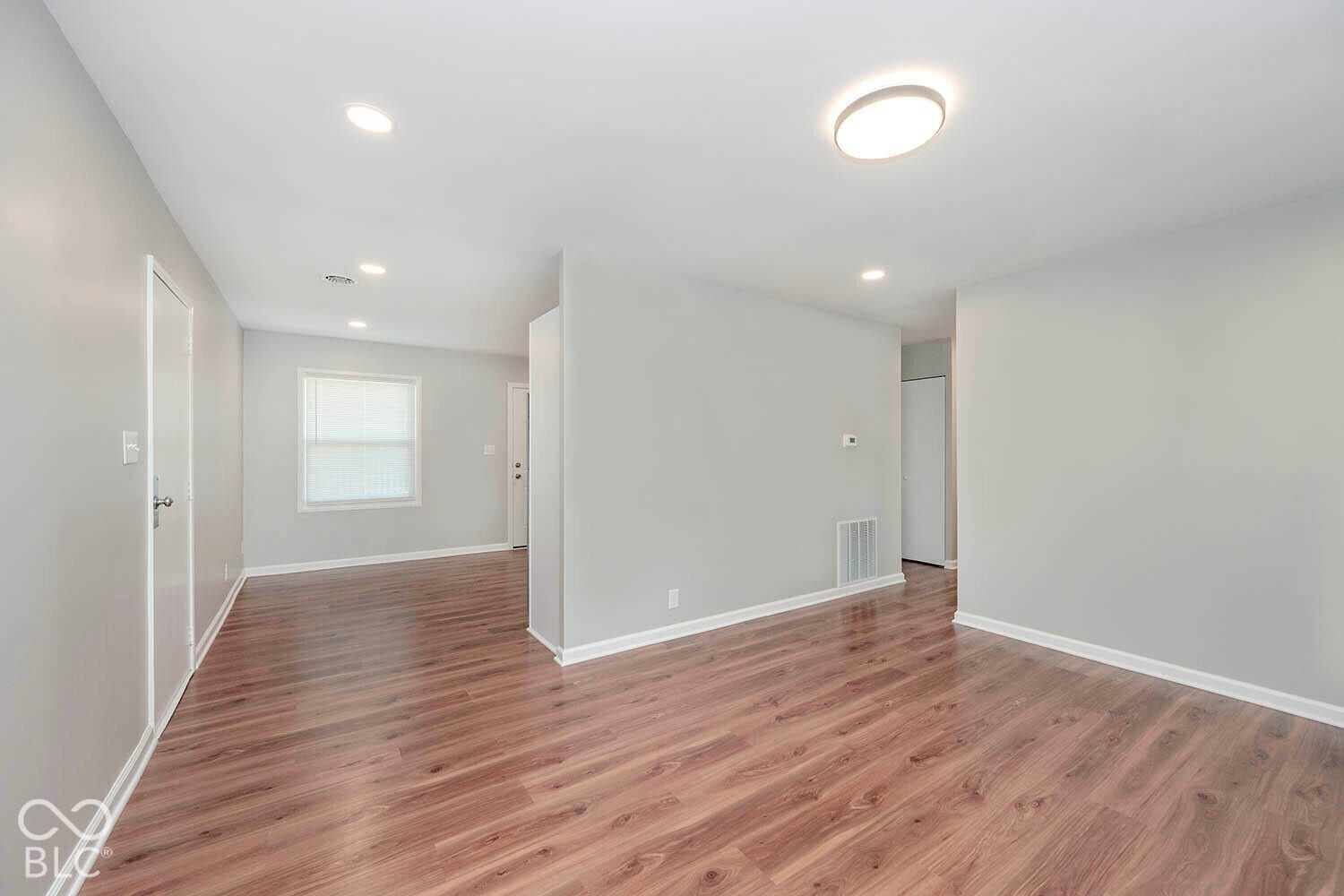 Wood-finish flooring throughout, recessed lighting, flush-mount ceiling light, white window blinds, and light gray wall paint