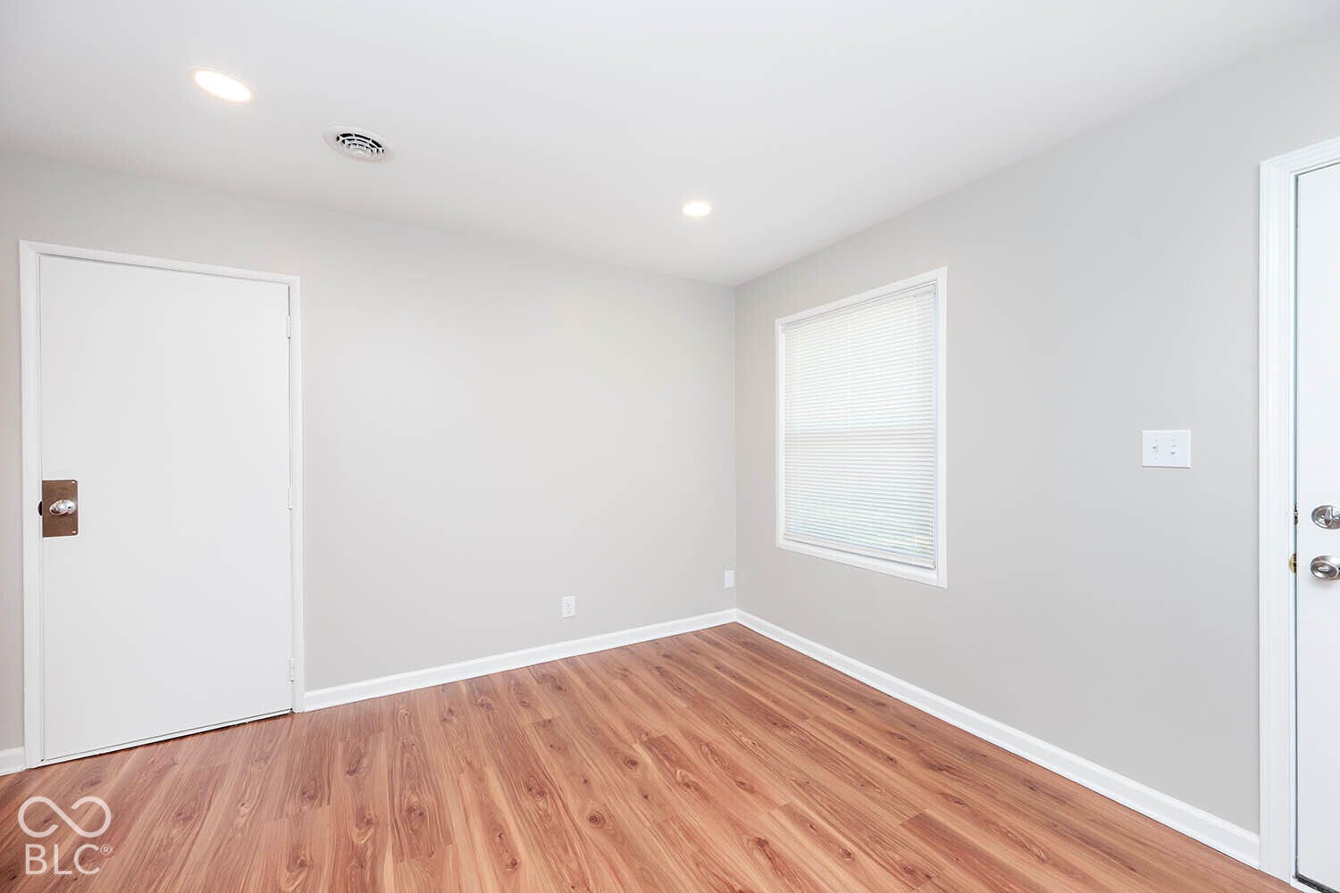 Wood-finish flooring with white trim, recessed ceiling lighting, and a white framed window