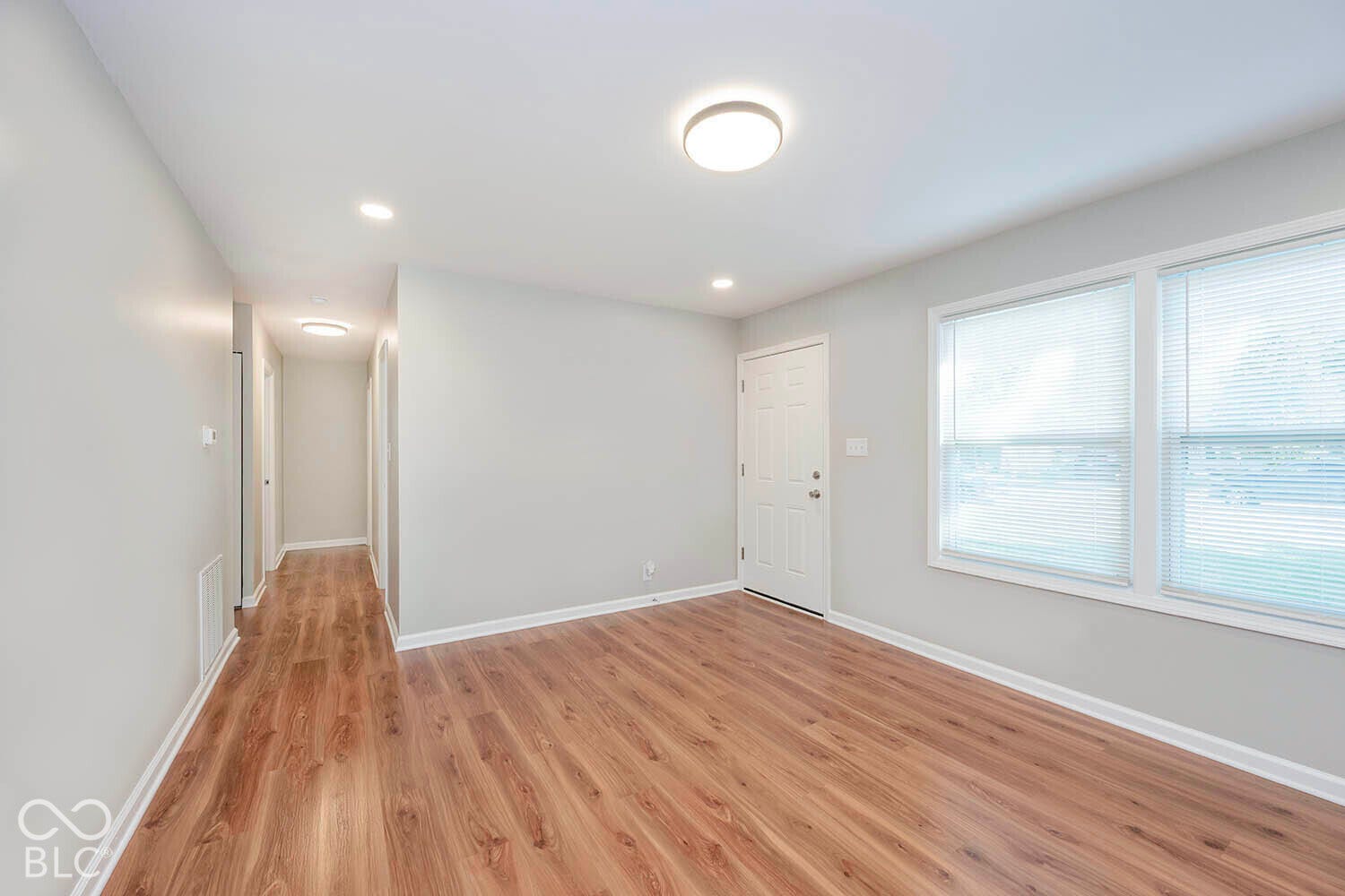 Spacious interior with wood-finish flooring, light grey wall paint, and recessed lighting