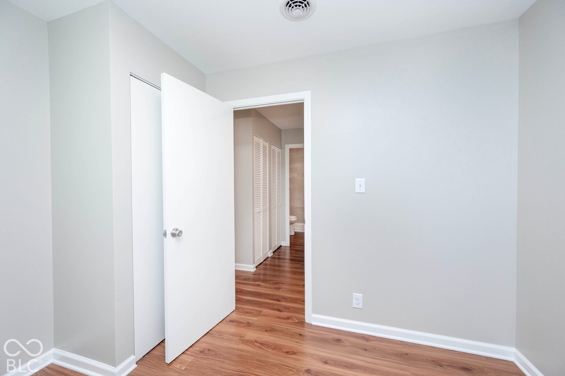Wood-finish flooring, white trim, and a white interior door