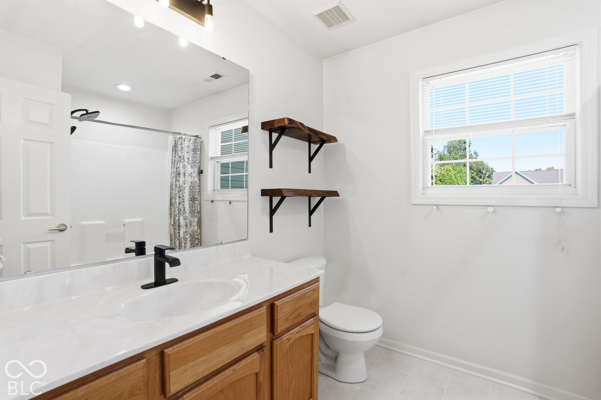 Single vanity with an integrated sink, wood-finish cabinetry, and a matte black faucet
