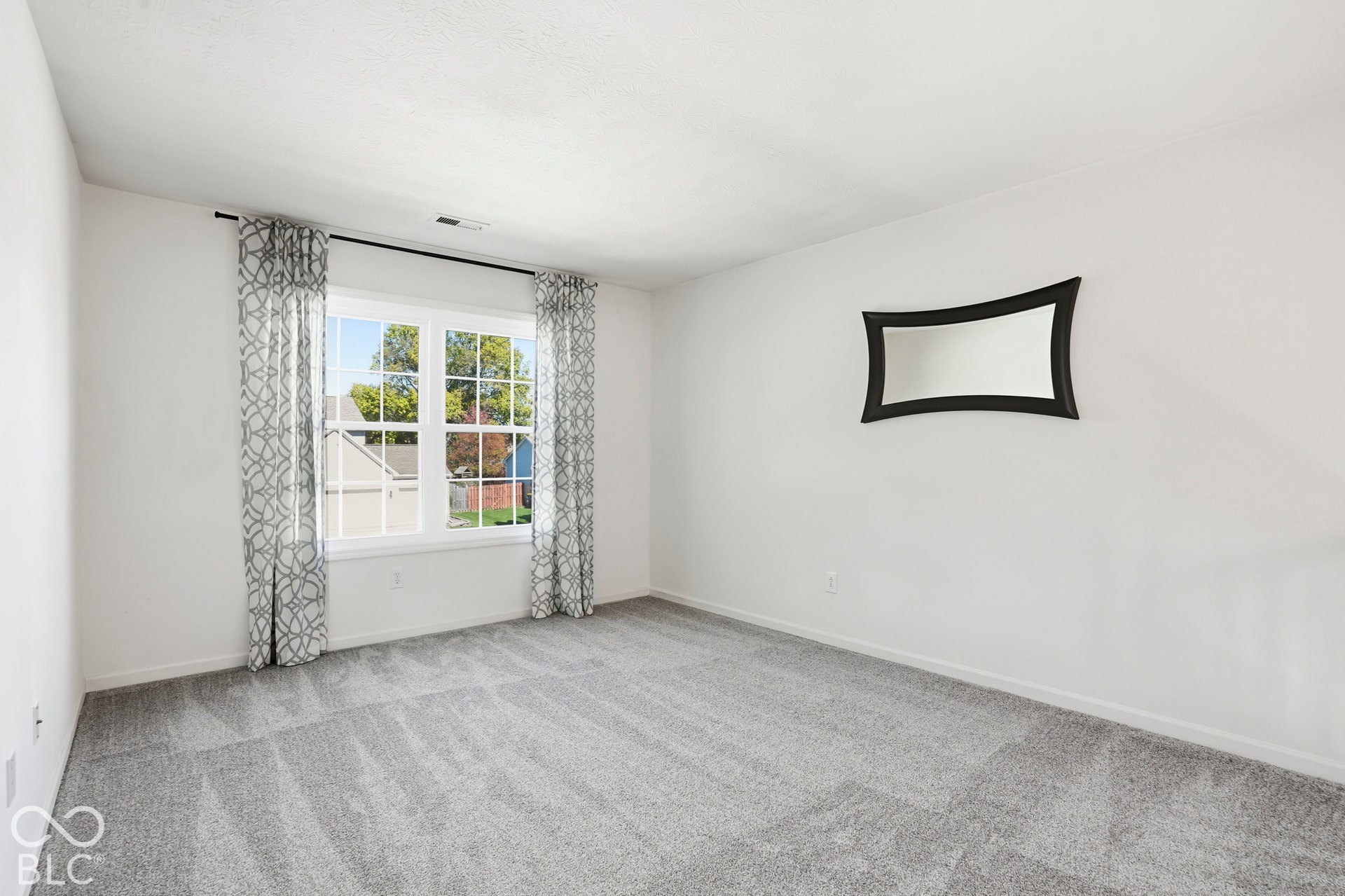 White wall finishes, light gray carpeting, and a large window with white trim