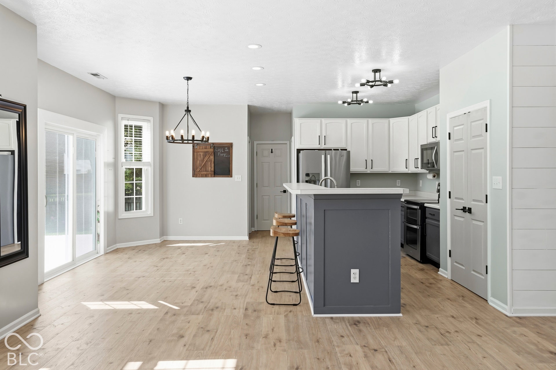 Kitchen island with seating, white shaker cabinetry, stainless steel appliances, and a sliding glass door