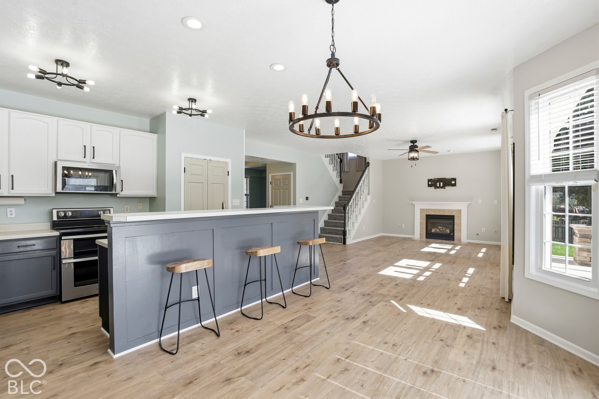 Kitchen featuring white upper cabinetry, dark lower cabinetry, stainless steel appliances, and a breakfast bar