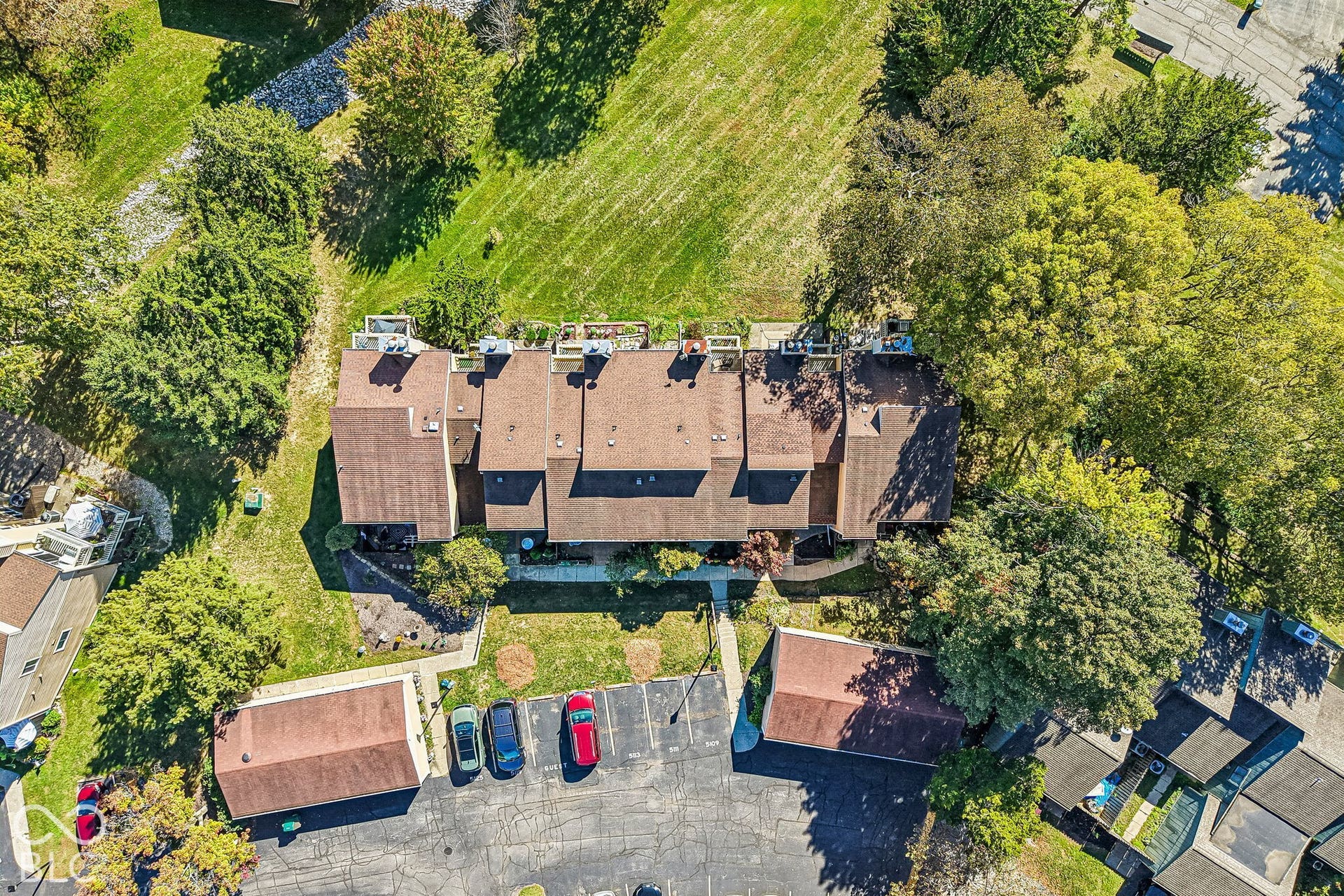 Townhome property featuring multiple units, surrounding green space, and mature trees