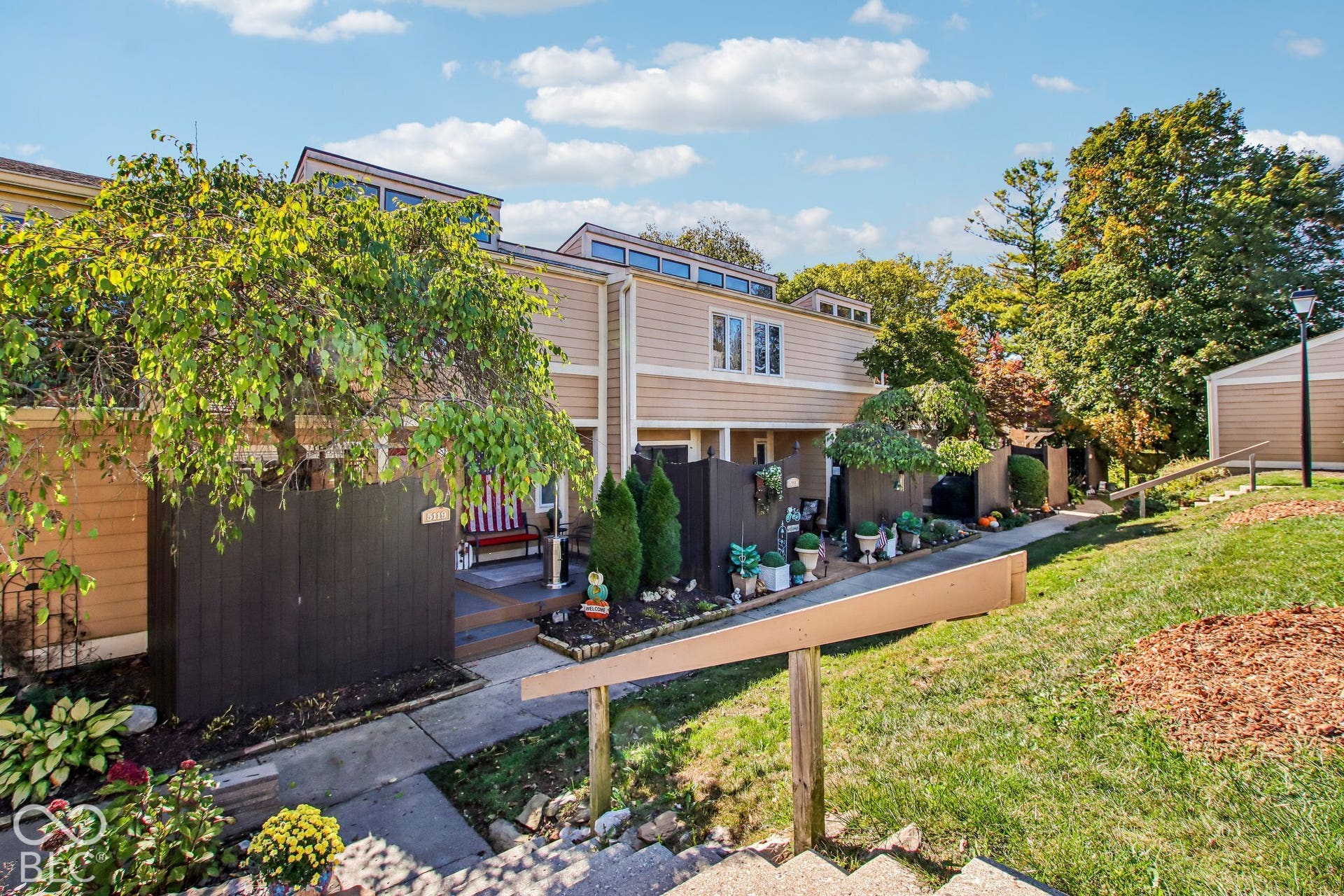 Exterior featuring siding, dormer windows, a private fenced patio, and a sloped lawn