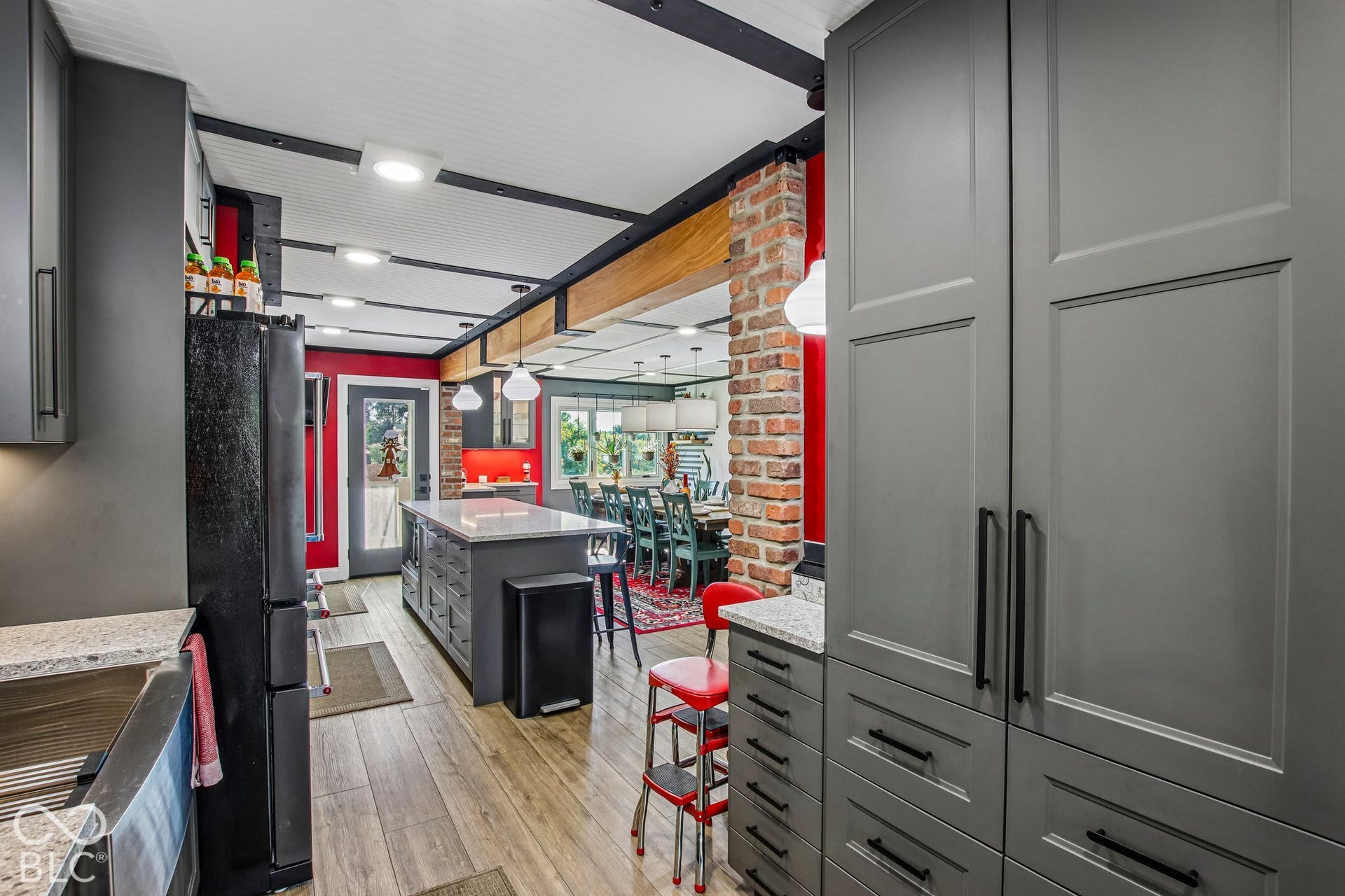Kitchen featuring wood-finish flooring, gray shaker-style cabinetry, granite countertops, and a center island with additional storage