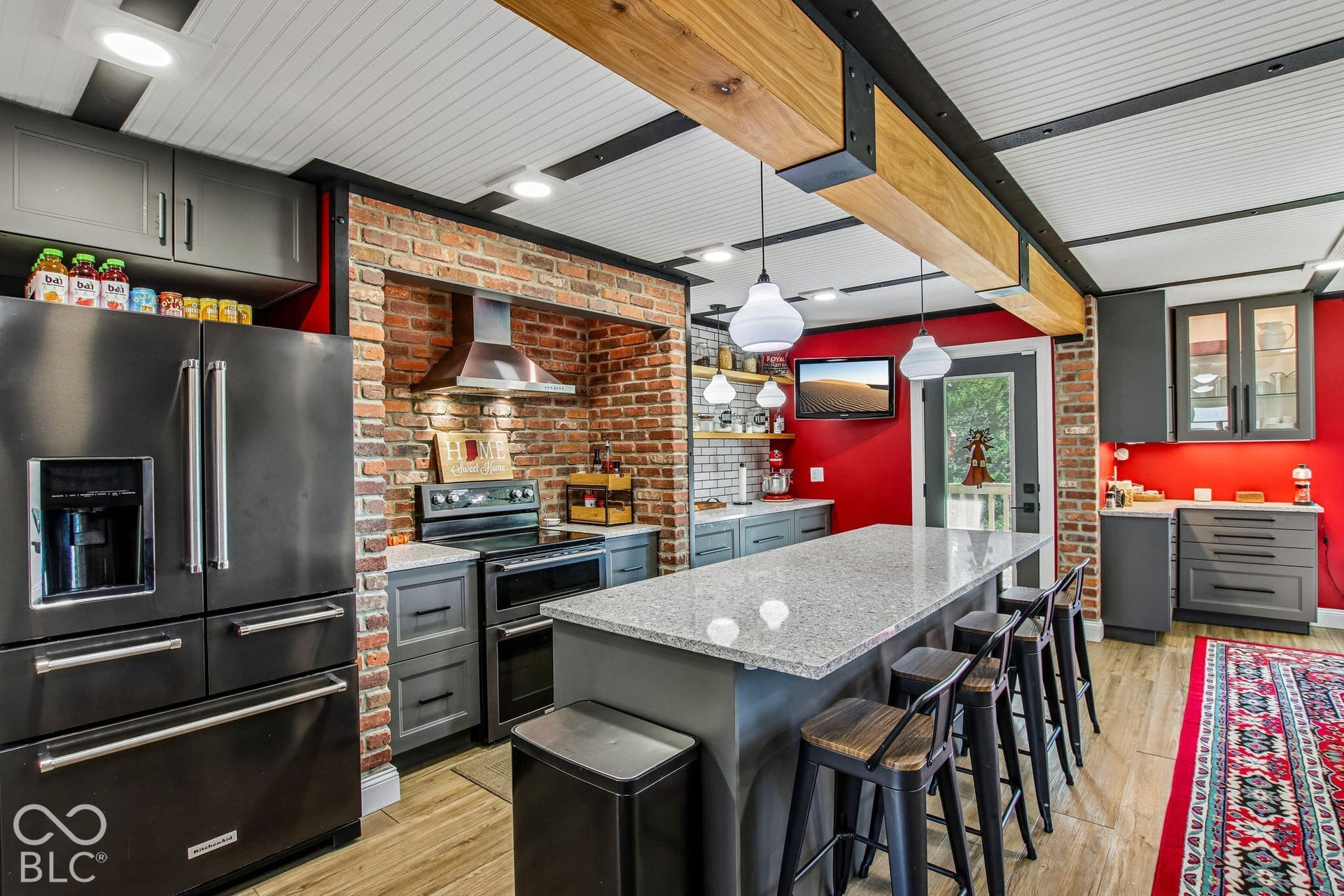 Exposed brick accent wall, wood-finish flooring, and a substantial island with seating