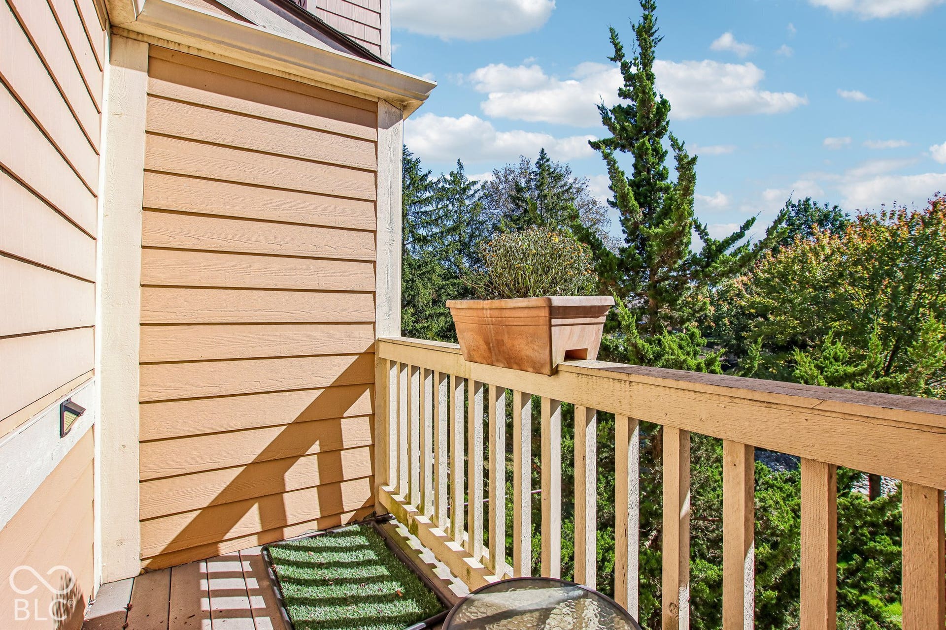 Outdoor balcony featuring horizontal siding, wooden railing, and a partial outdoor light fixture